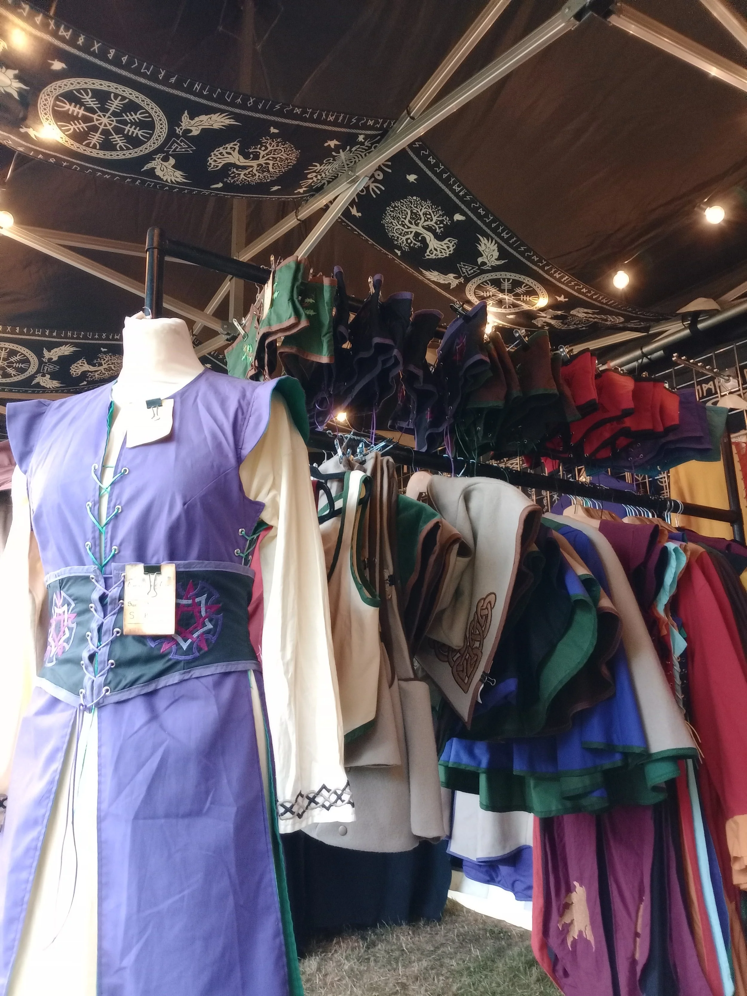 Costumes and clothing on display at a stall with Viking-themed decorations on the ceiling.