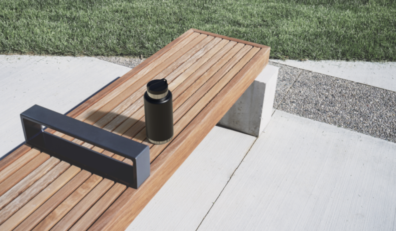 Black insulated travel mug on a wooden bench outside on a sunny day with grass and concrete surrounding it.