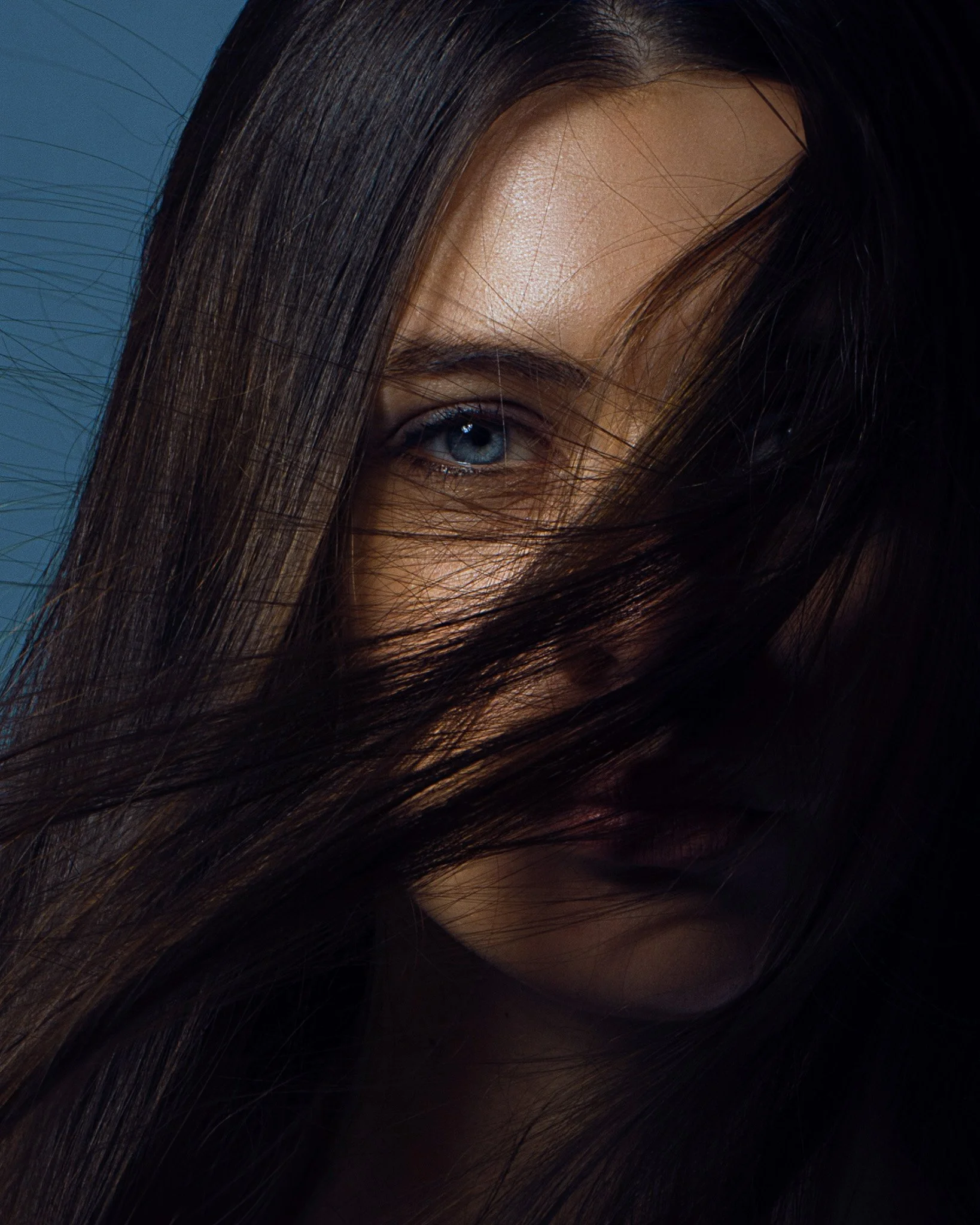 Blue eyed brunette woman with center parted hair covering face