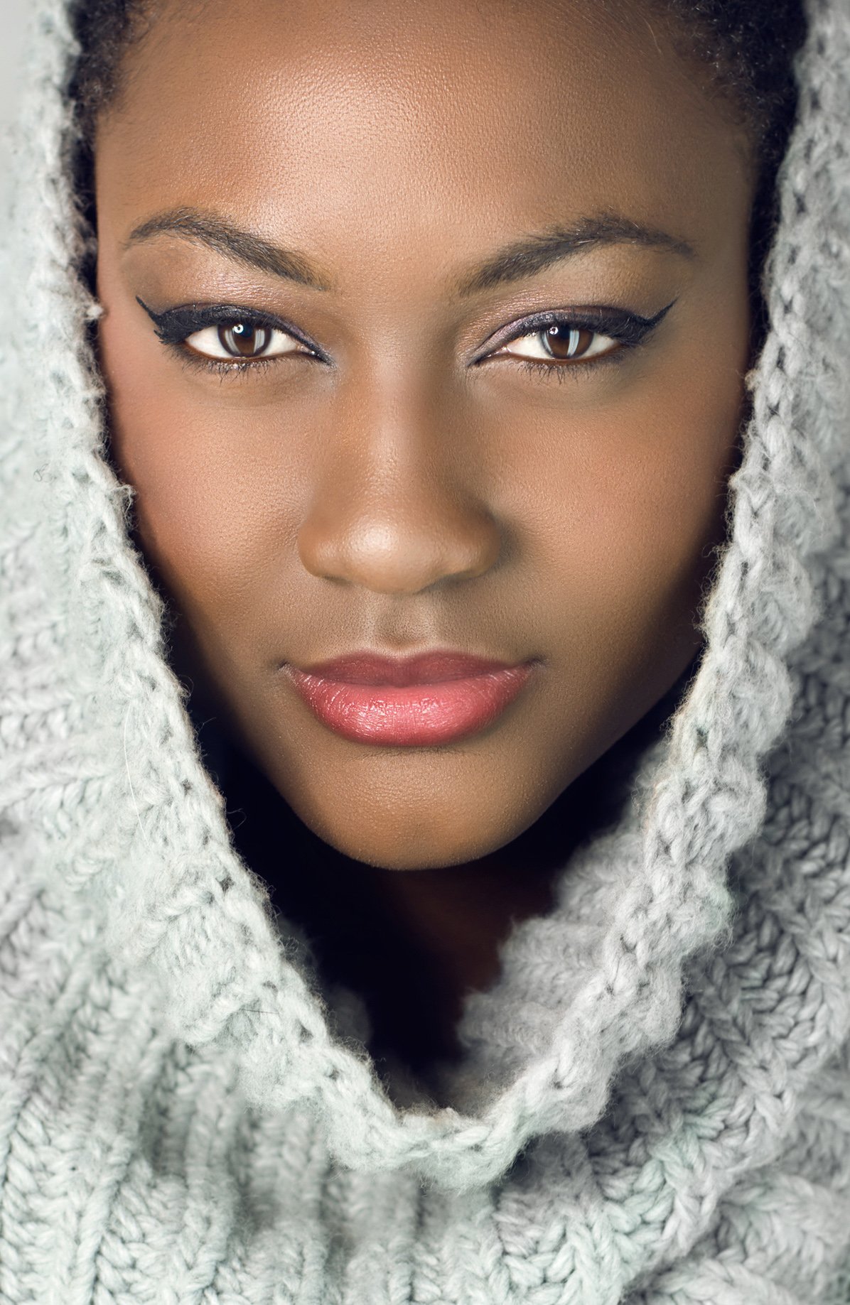 Black woman with gray headscarf, classic winged eyeliner and soft makeup