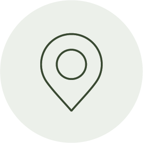 A green map pin icon on a light gray circular background.