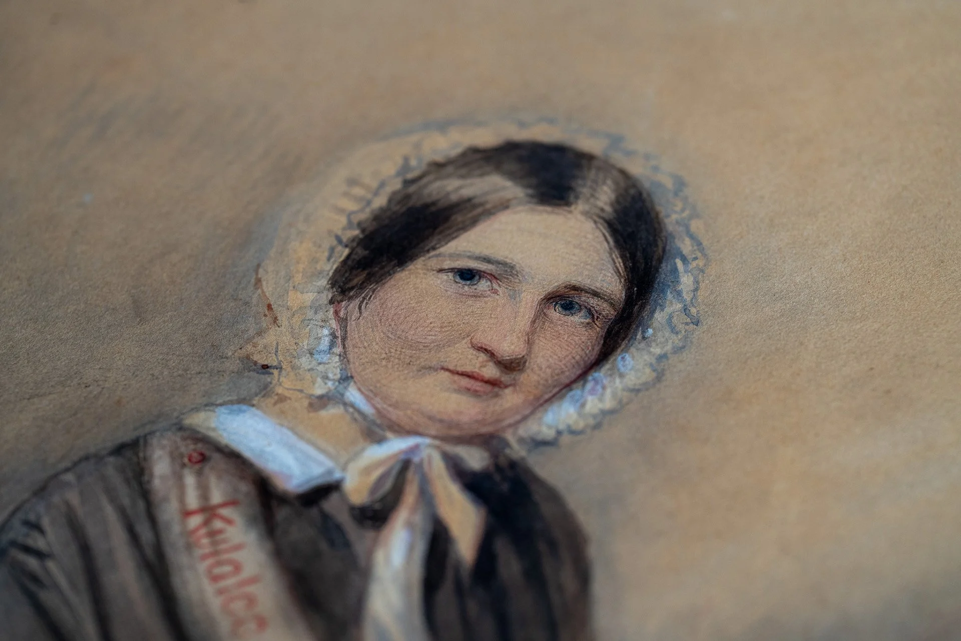 Close-up of a banknote featuring a portrait of a woman with dark hair, blue eyes, wearing a white collar and a ribbon tied at her neck.