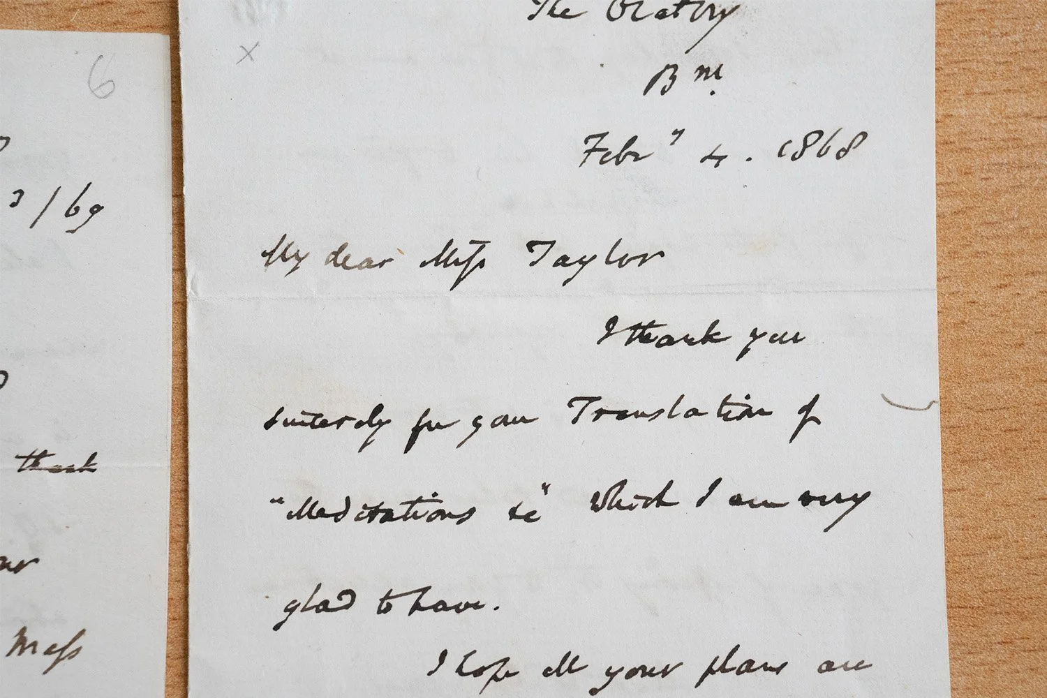 Photograph of an old handwritten letter from February 4, 1868, on cream paper, placed on a wooden surface.
