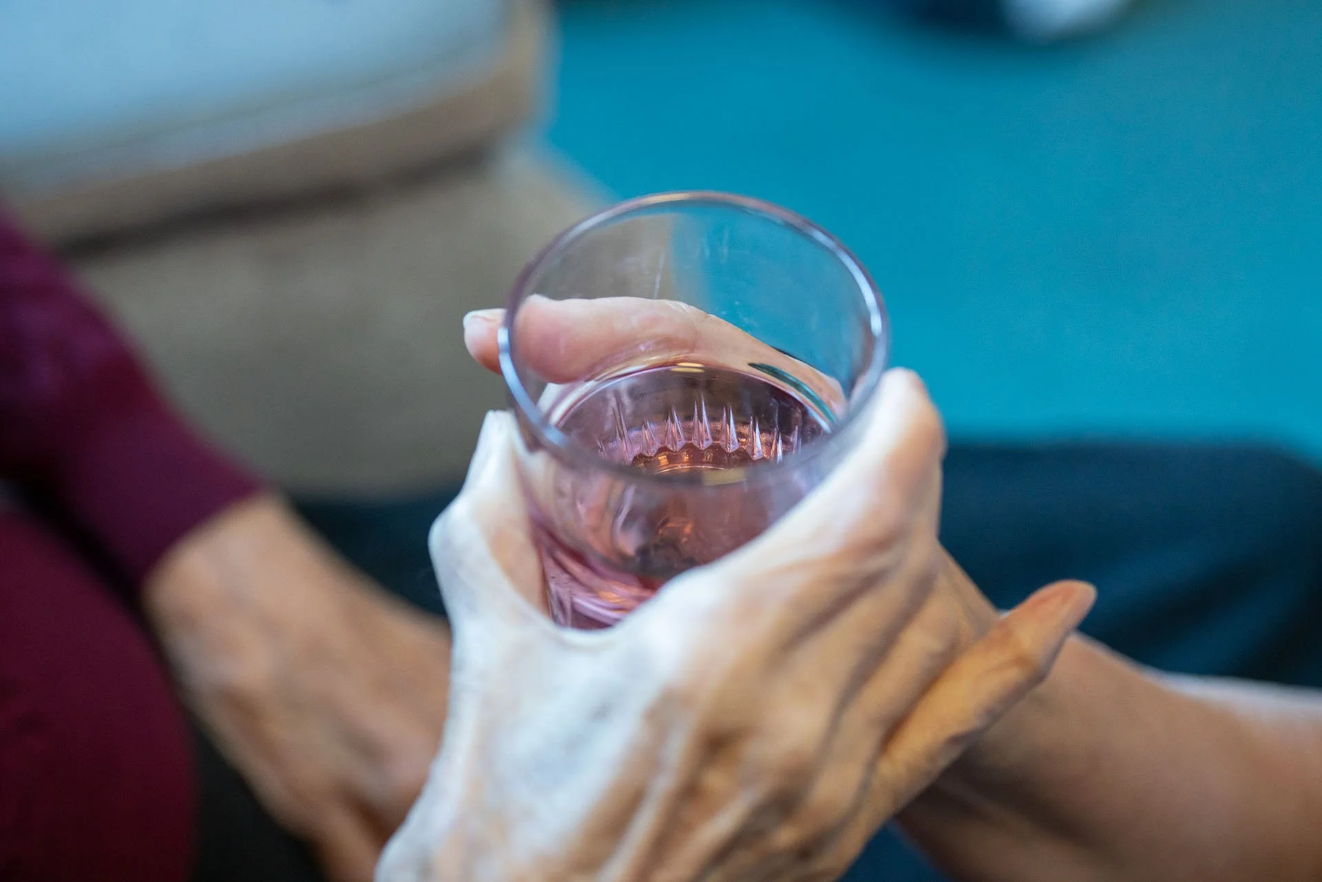 Person holding a glass of pink-colored beverage with their right hand.