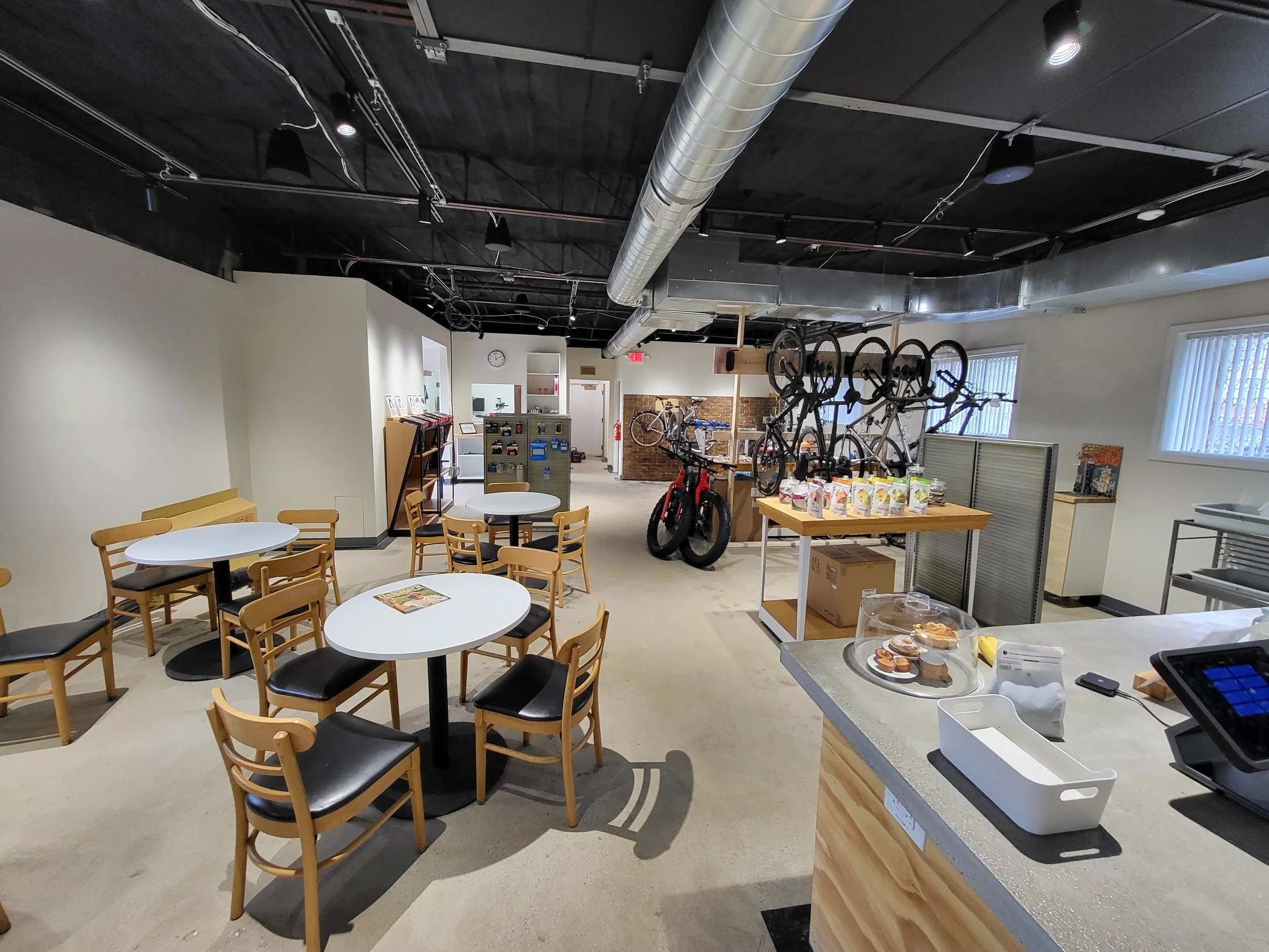 The interior of DAS VELO with cafe tables, coffee, and a bike repair area