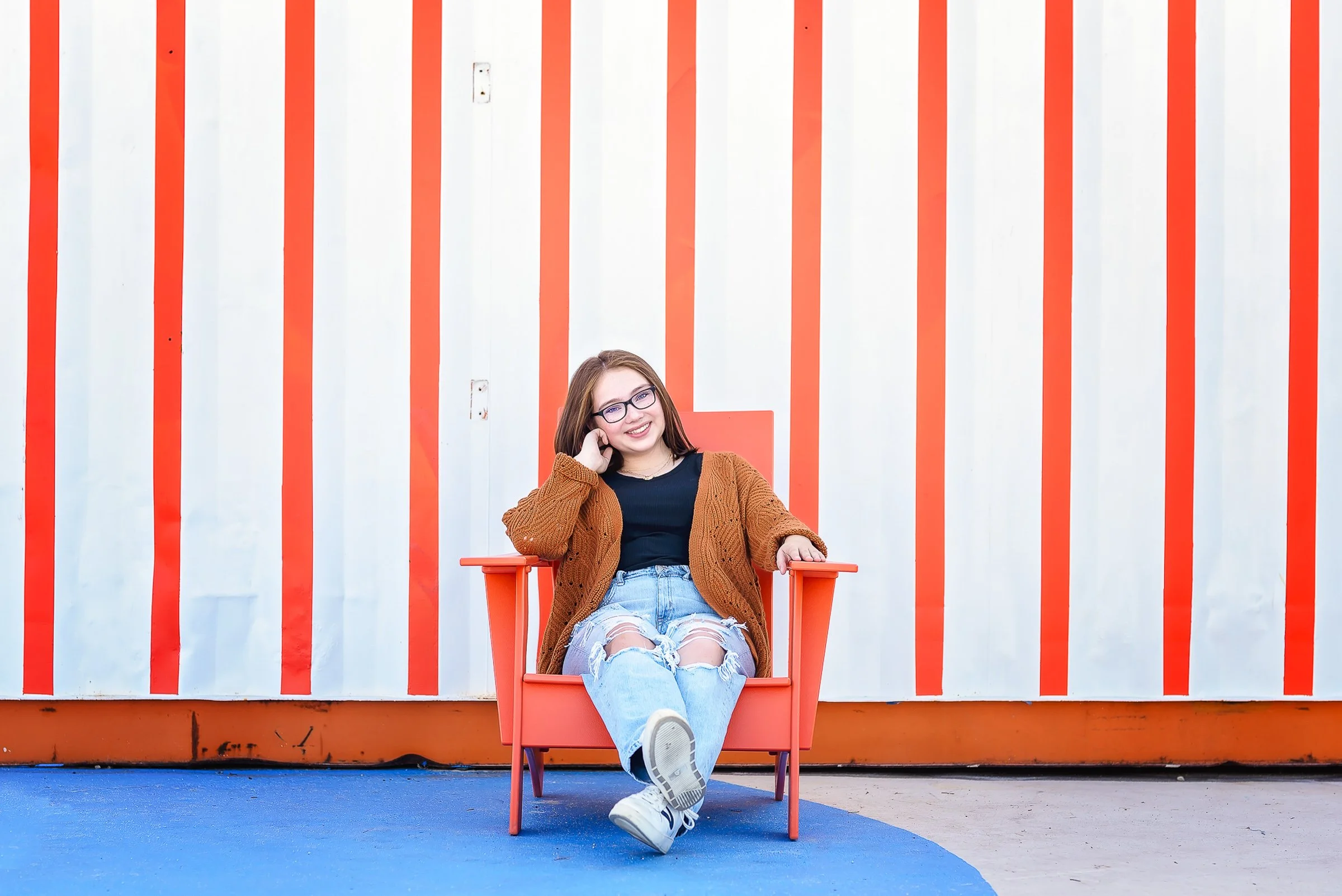 senior portrait in front of orange and white painted backdrop at camp north end