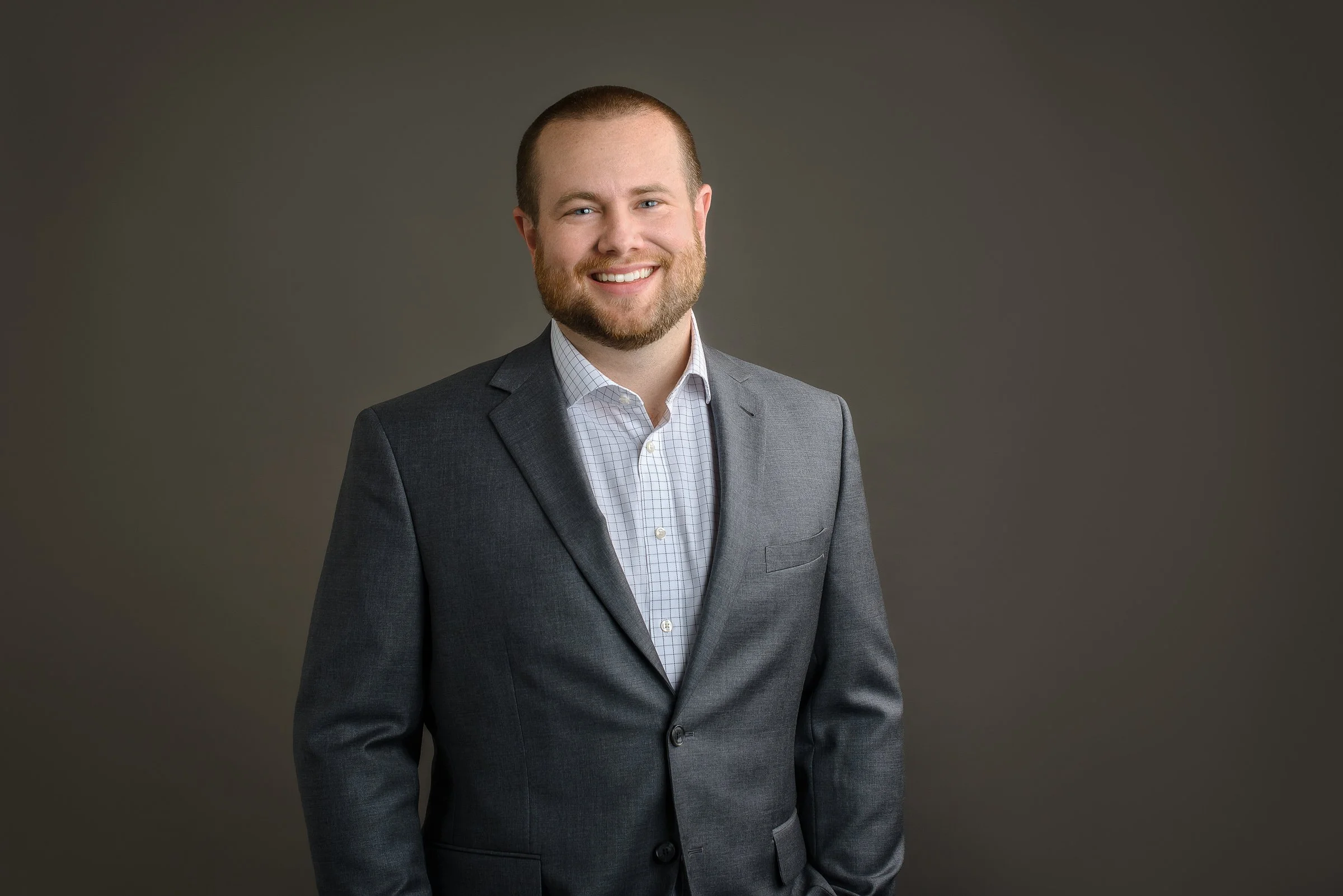 Professional headshot of a man wearing a gray suit on a neutral studio background in Charlotte NC