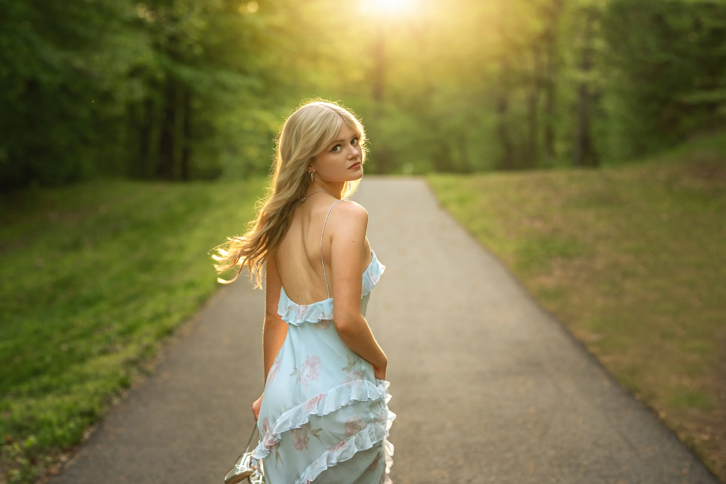 gastonia area high school senior looking over shoulder as she walks on a path in the sunlit woods in charlotte nc