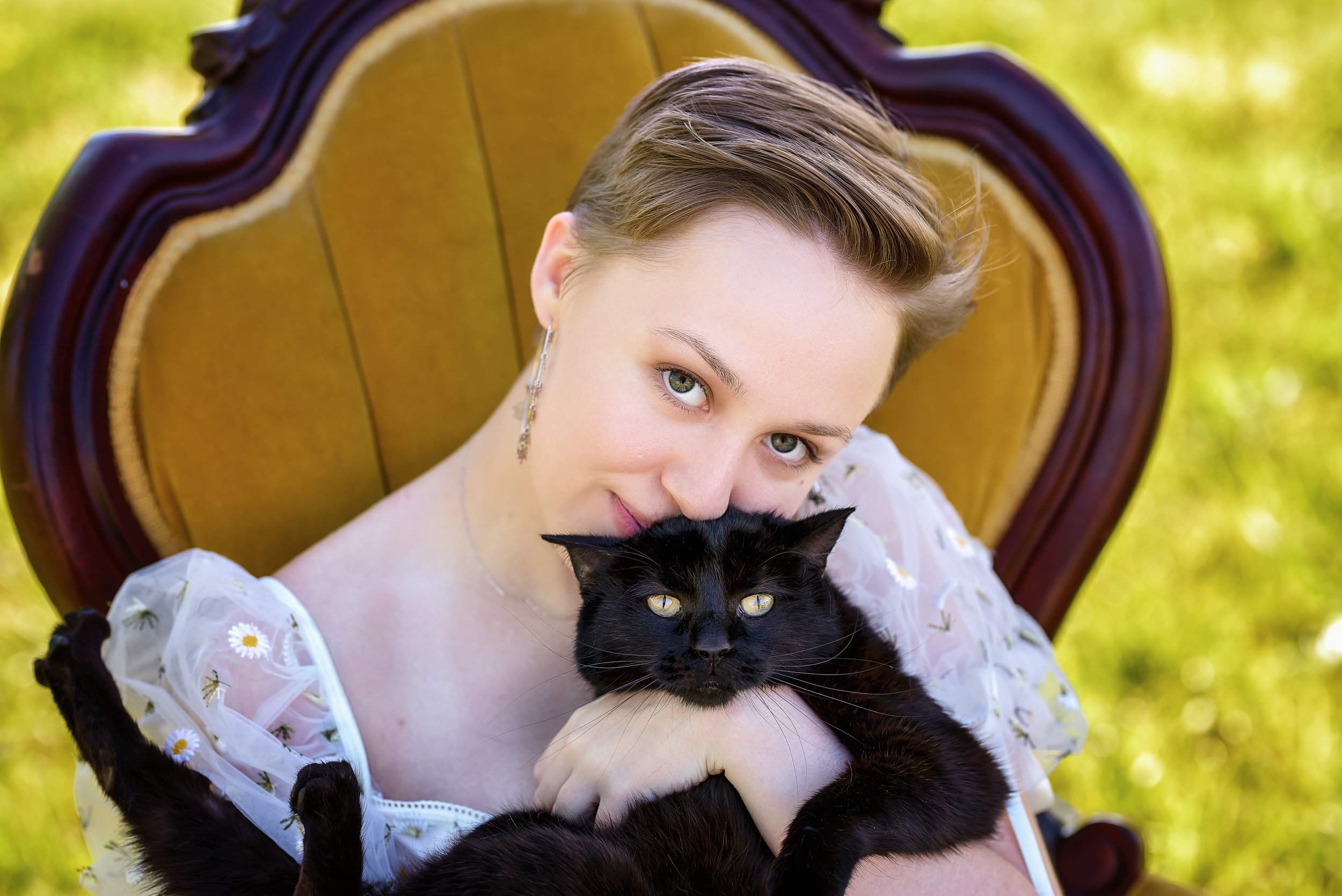 Close-up portrait of a senior girl holding a black cat outdoors