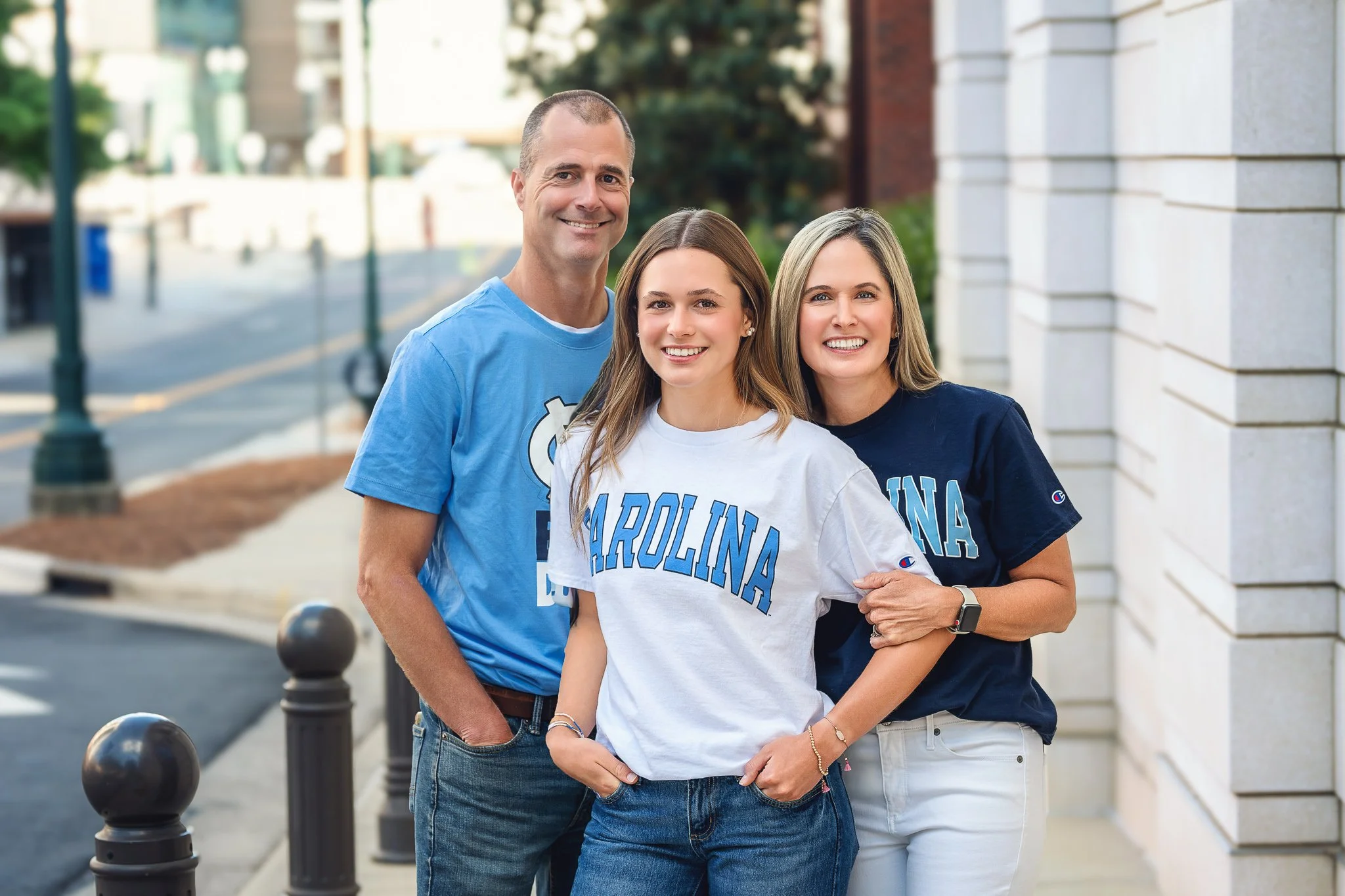 High school senior with parents wearing University of North Carolina apparel after committing to college.