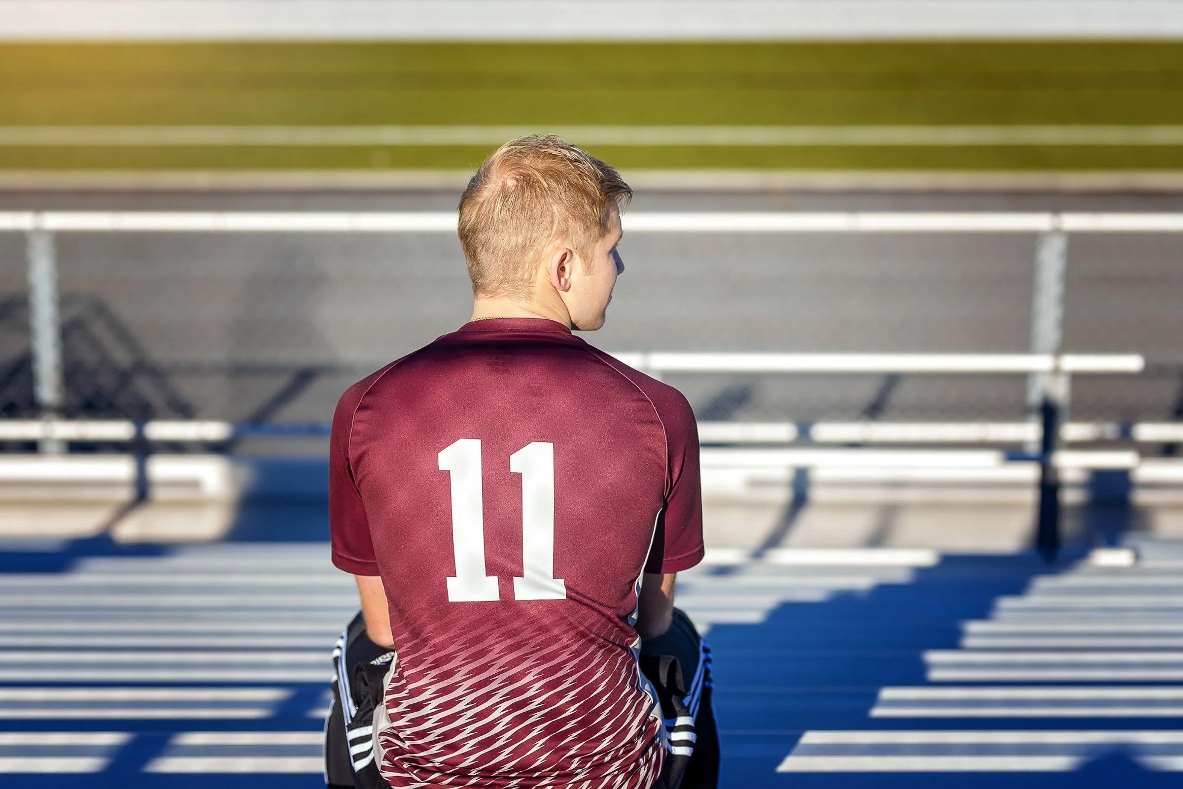 emotional portrait of high school soccer player in bleachers from behind in jersey