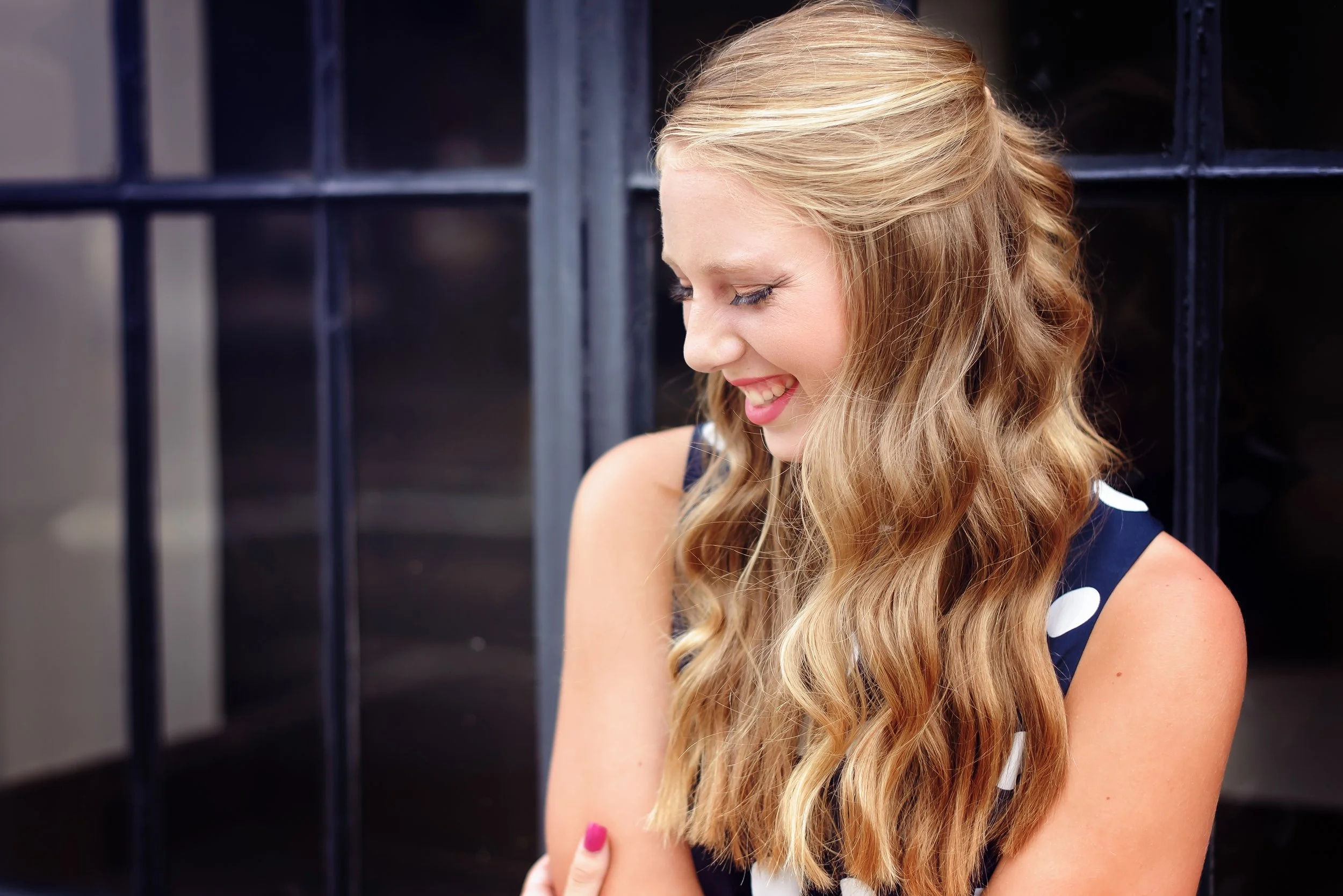 Editorial senior portrait of a Charlotte high school senior girl photographed in an urban setting with a cinematic aesthetic in polka dot dress