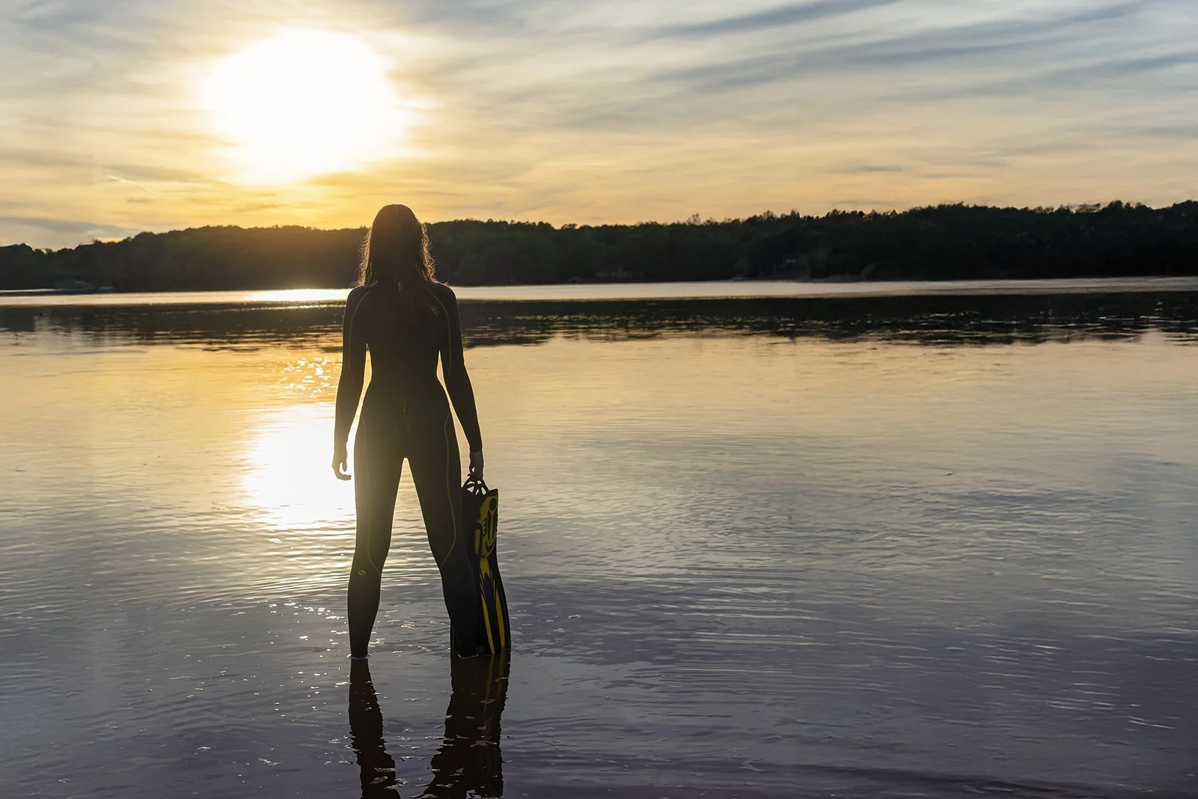 concord area senior in north carolina photographed for senior portraits at a lake in a wetsuit at sunset