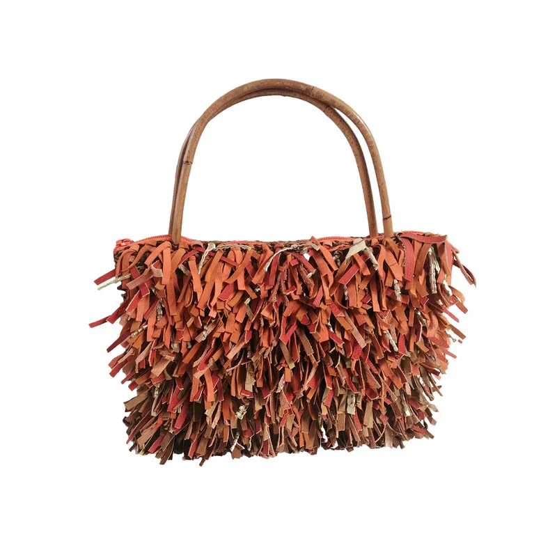 Eine Tasche mit Fransen aus Leder in Braun- und Rottönen, mit einem runden Holzgriff von Maike Weyrich.