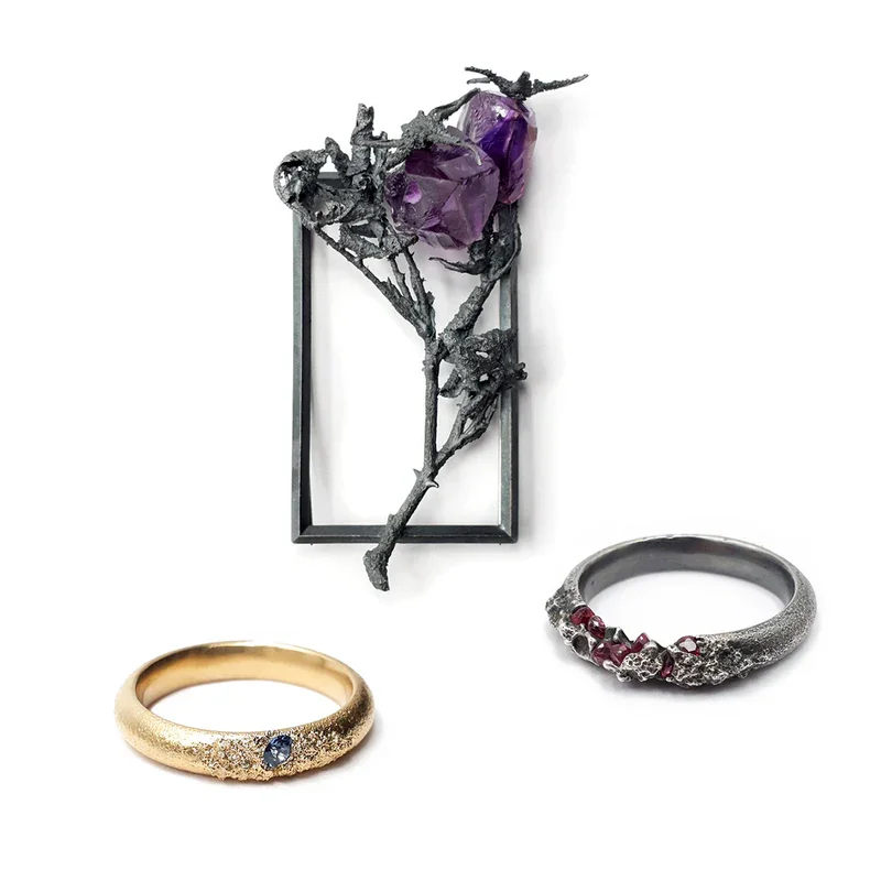 Zwei Ringe und eine metallene Skulptur mit Edelsteinen, die aussieht wie eine getrocknete Blume, von Alvaro-Luca Ellwart