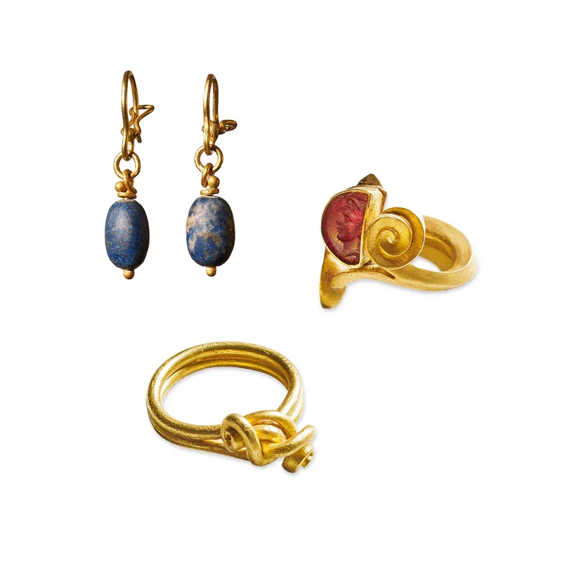 Goldene Schmuckstücke, darunter Ohrringe mit blauen Steinen, ein goldener Ring mit rotem Stein und ein weitererGoldring von Wolfgang Skoluda
