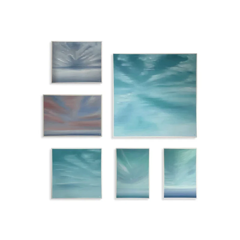 Sechs Gemälde einer Himmelsszene mit Wolken, in verschiedenen Blautönen, in einem weißen Rahmen an einer weißen Wand von Claudia Storost