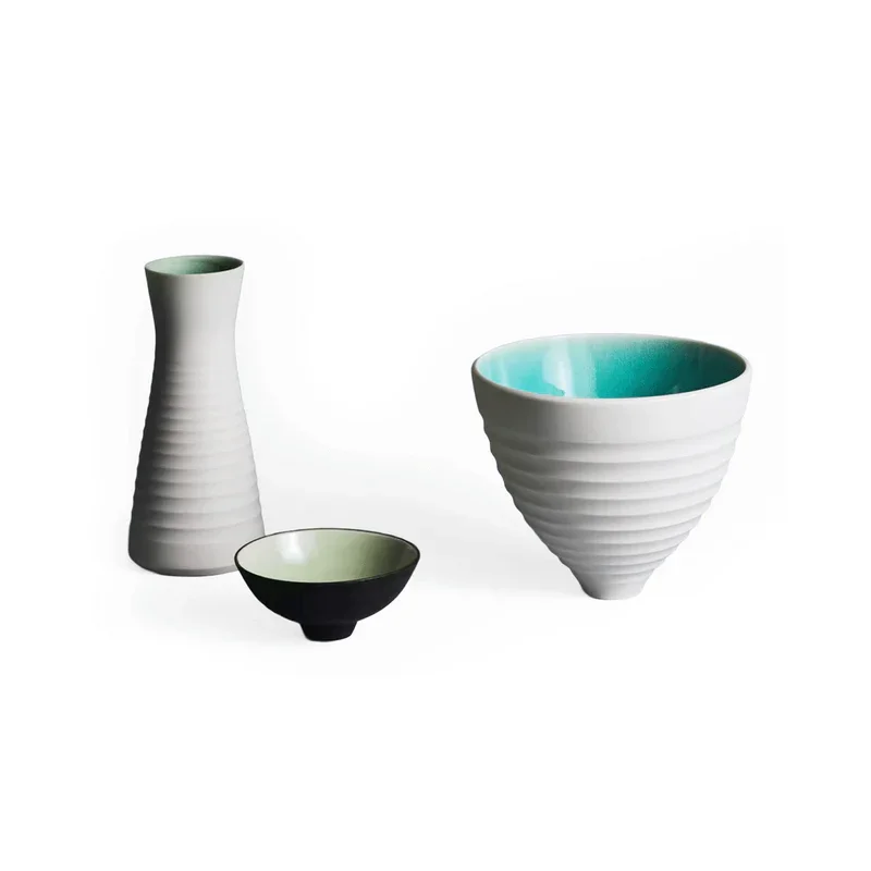 Drei keramische Schalen und Vasen mit horizontalen Rillen, eine weiße Vase hoch auf der linken Seite, eine kleinere schwarze Schale in der Mitte, und eine große Schale rechts von Lars Kanter