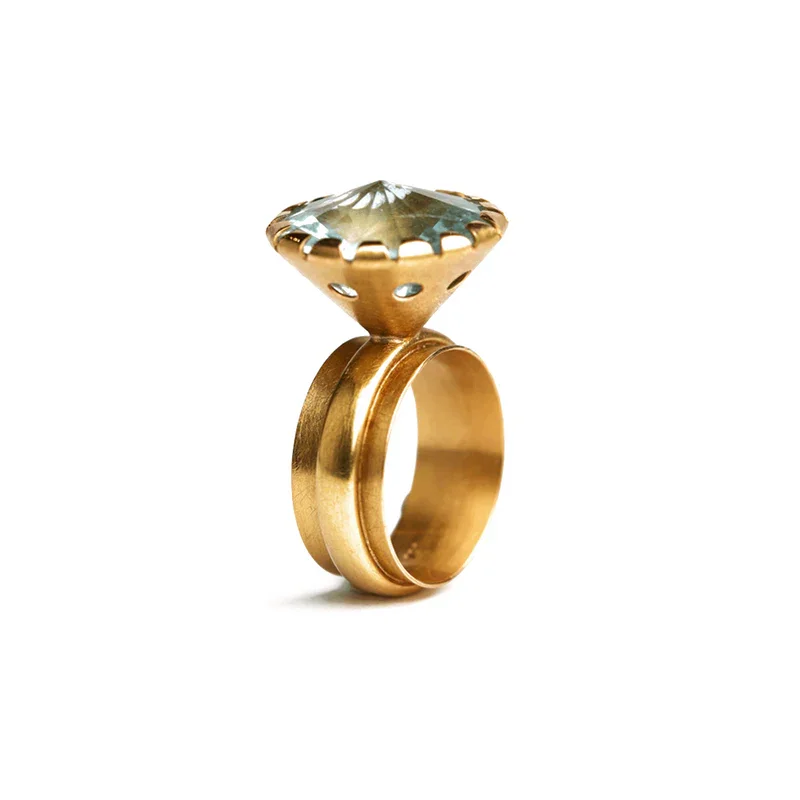 Ein goldener Ring von Marjon Reinsberger mit einem großen, funkelnden Edelstein auf einem weißen Hintergrund.