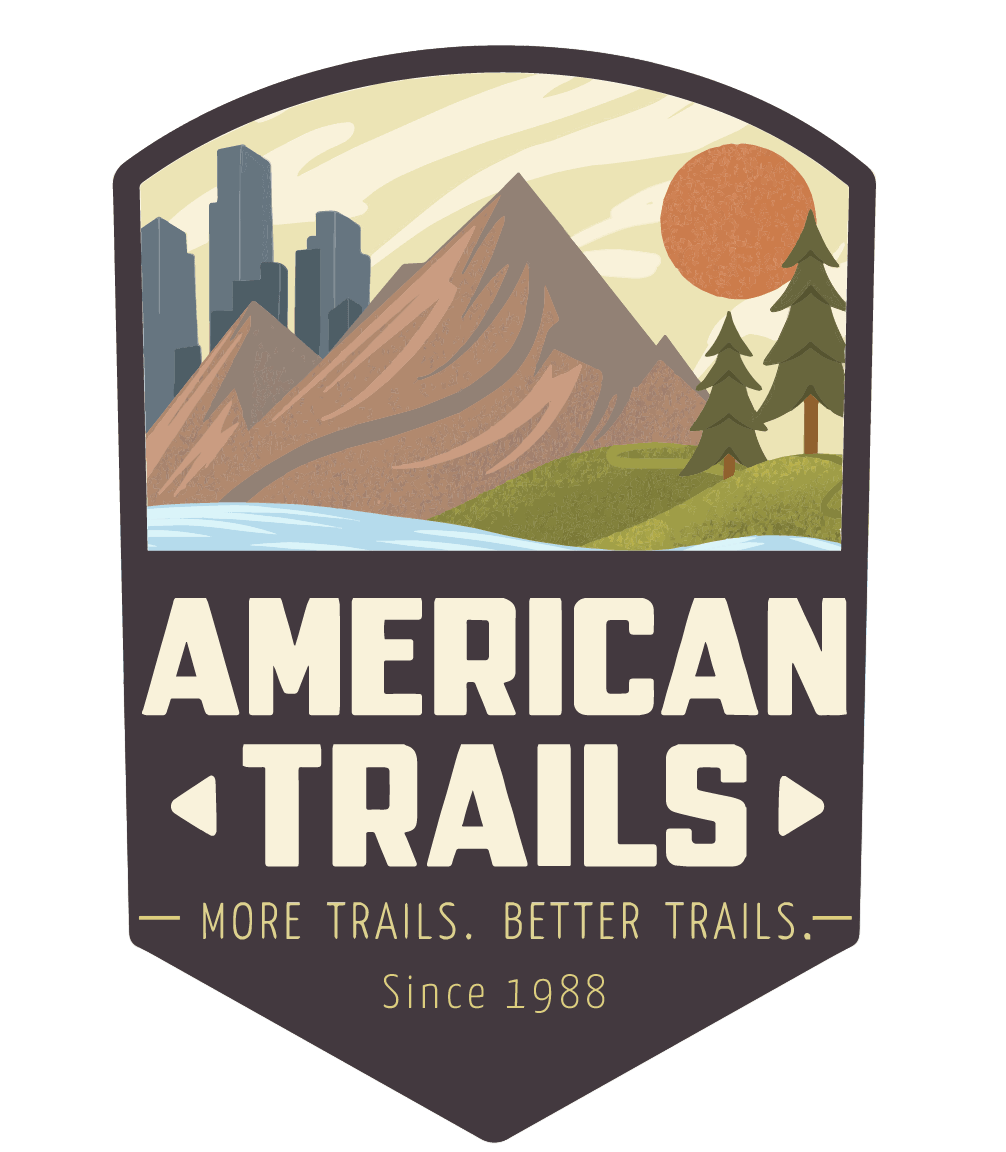Illustration featuring mountain landscapes, trees, a river, a sun, and city skyscrapers, with the text "American Trails" and the slogan "More Trails. Better Trails." since 1988.