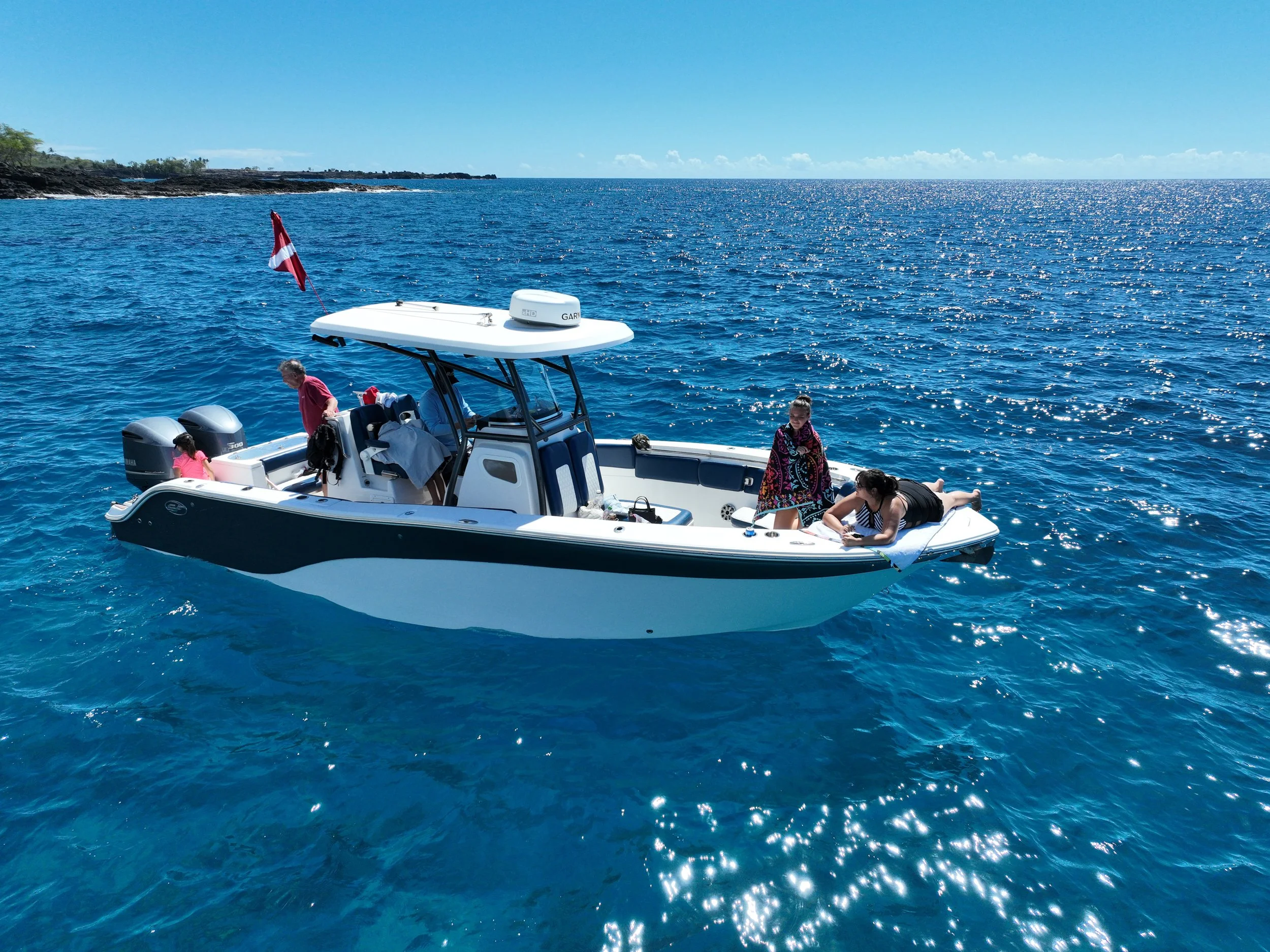 A boat with four women and one man on the water with land in the background.