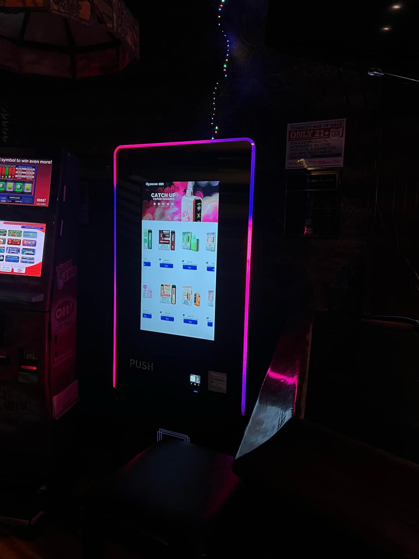 Modern vape vending machine with illuminated LED border in a low-light bar or nightclub environment, designed for in-venue convenience and visibility.