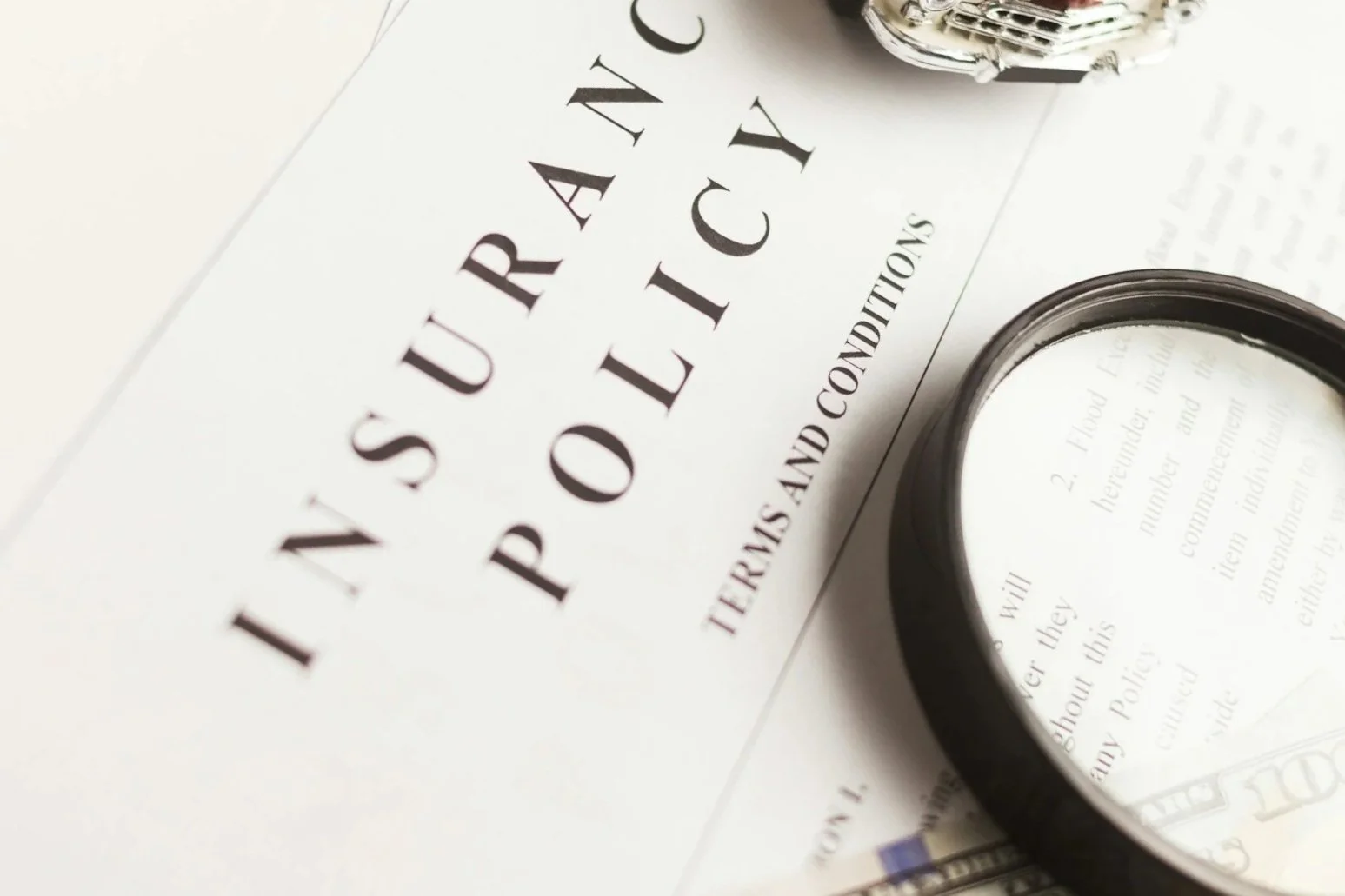 Book titled 'Insurance Policy' with glasses and papers on the table.