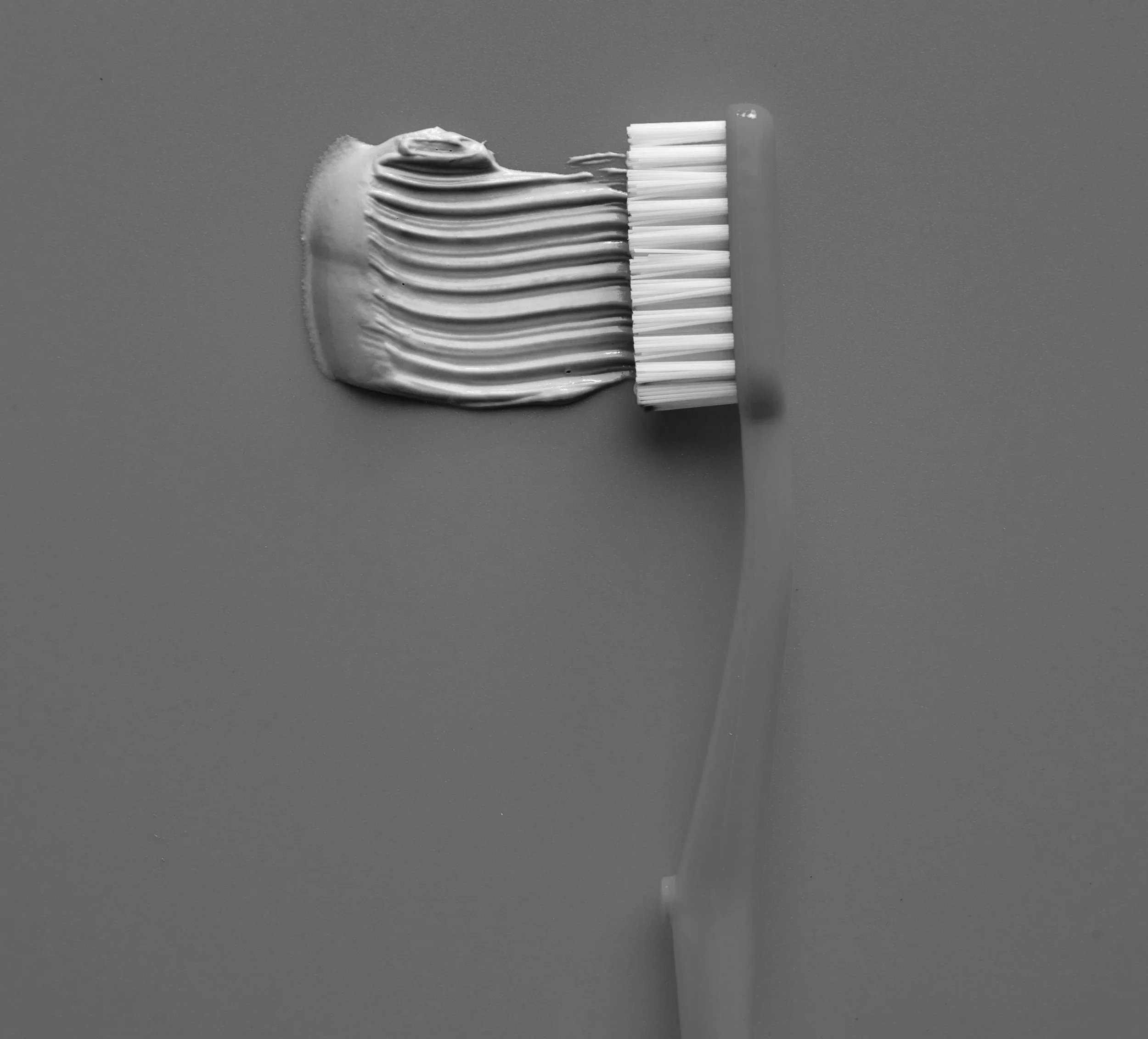 A close-up of a toothbrush with toothpaste on it against a plain background.