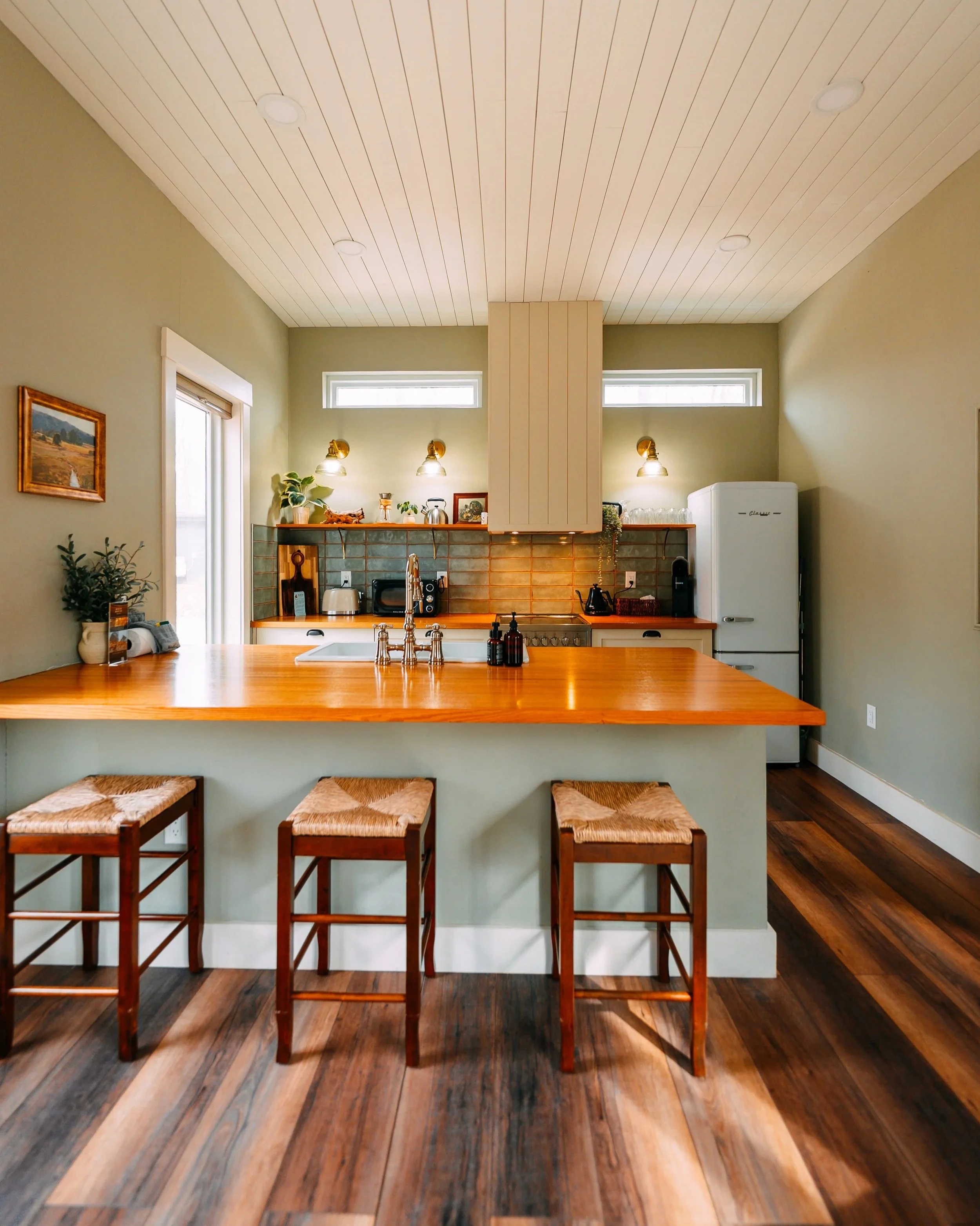 Sage-green and warm-wood kitchen designed for a short-term rental at Wilder Cabins