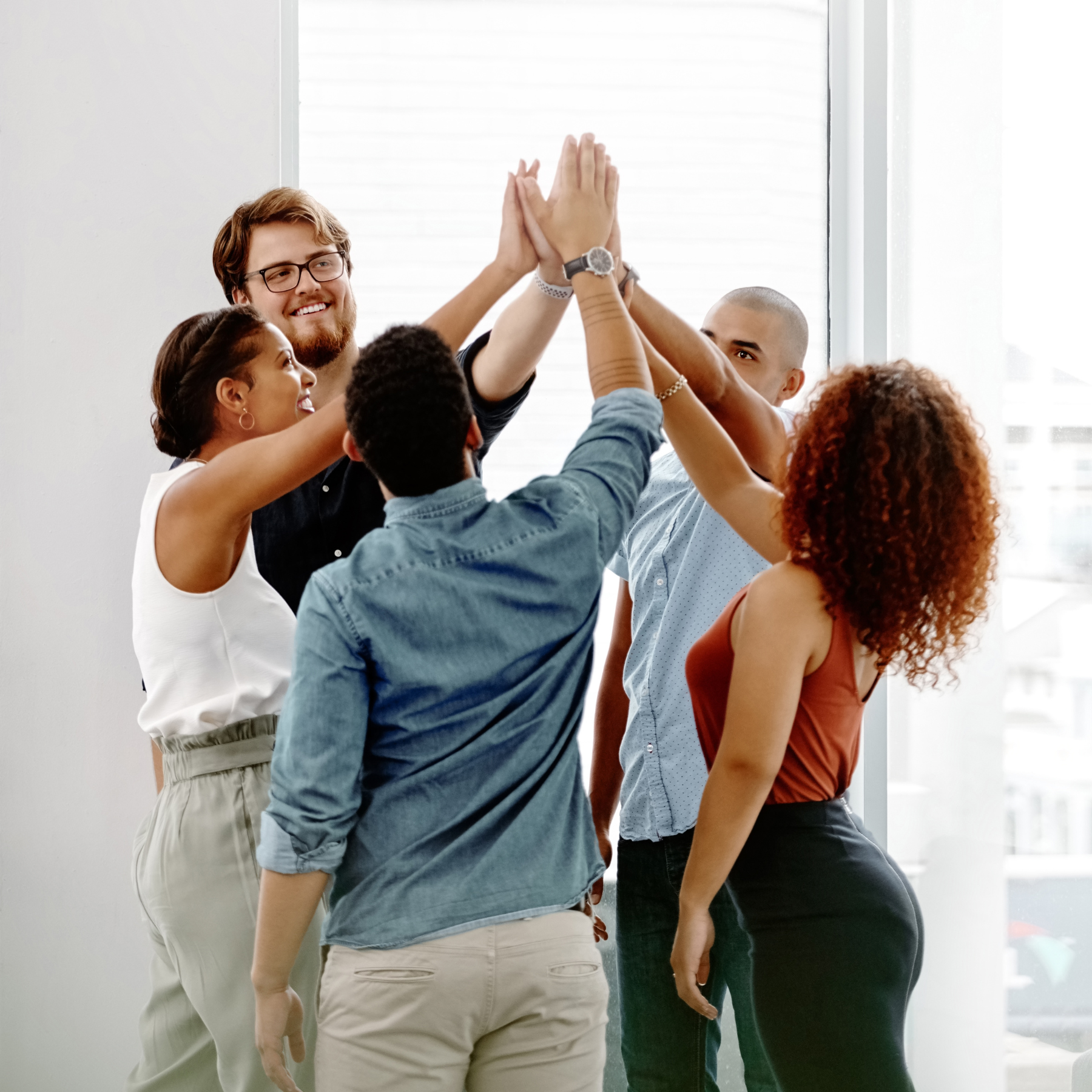 Diverse team of professionals celebrating with a high-five, representing BSP's collaborative approach to employee benefits strategy