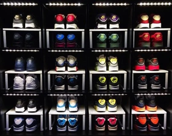 A display of colorful sneakers arranged on black shelves with LED lights in the background.