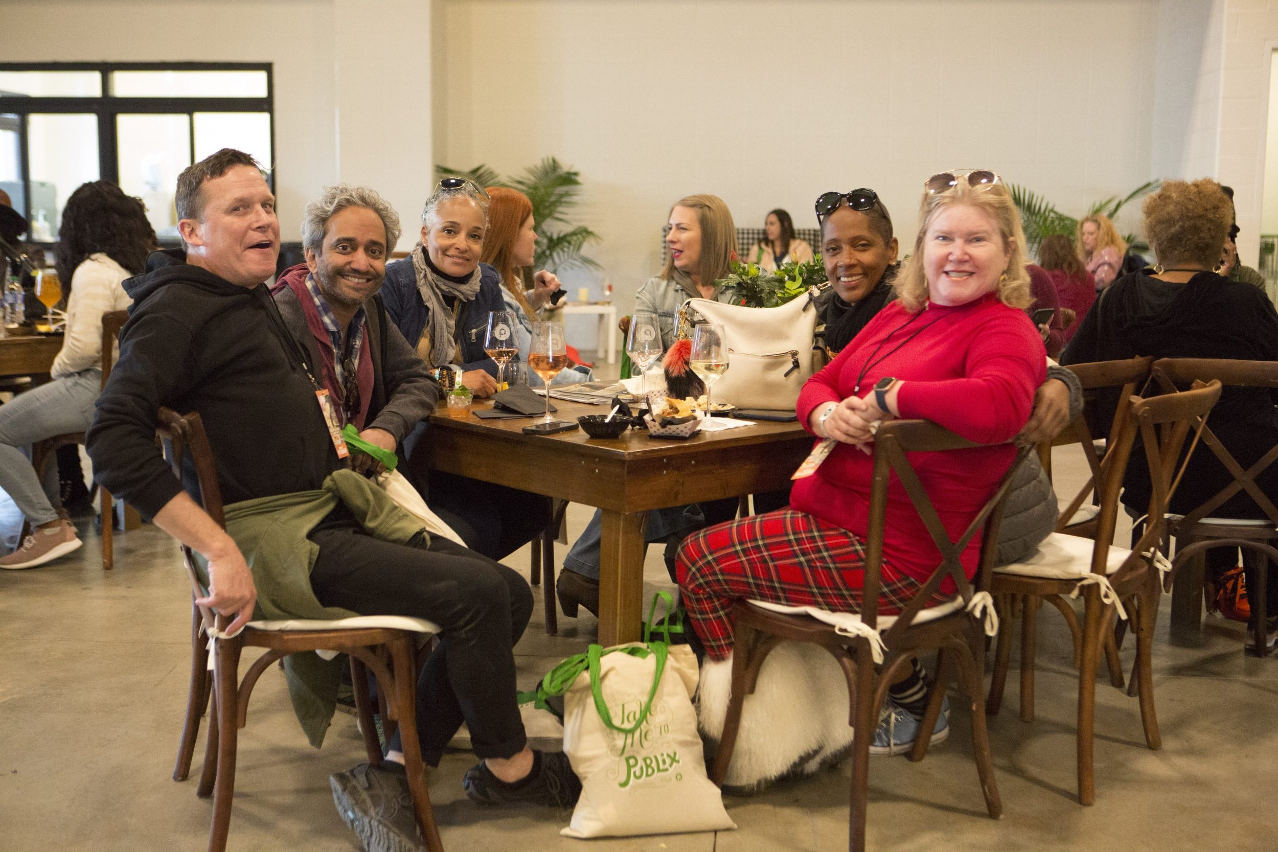 Group of six diverse people sitting around a table enjoying food and drinks at a restaurant or cafe.