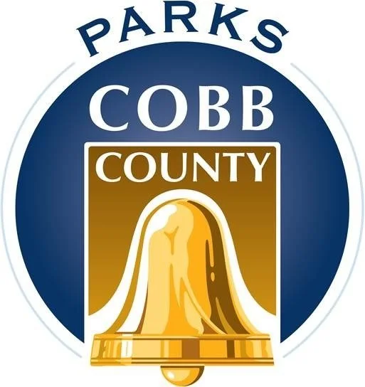 Logo for Cobb County Parks featuring a gold bell with a white handle on a gold background, surrounded by a blue circle with the words 'Parks Cobb County'
