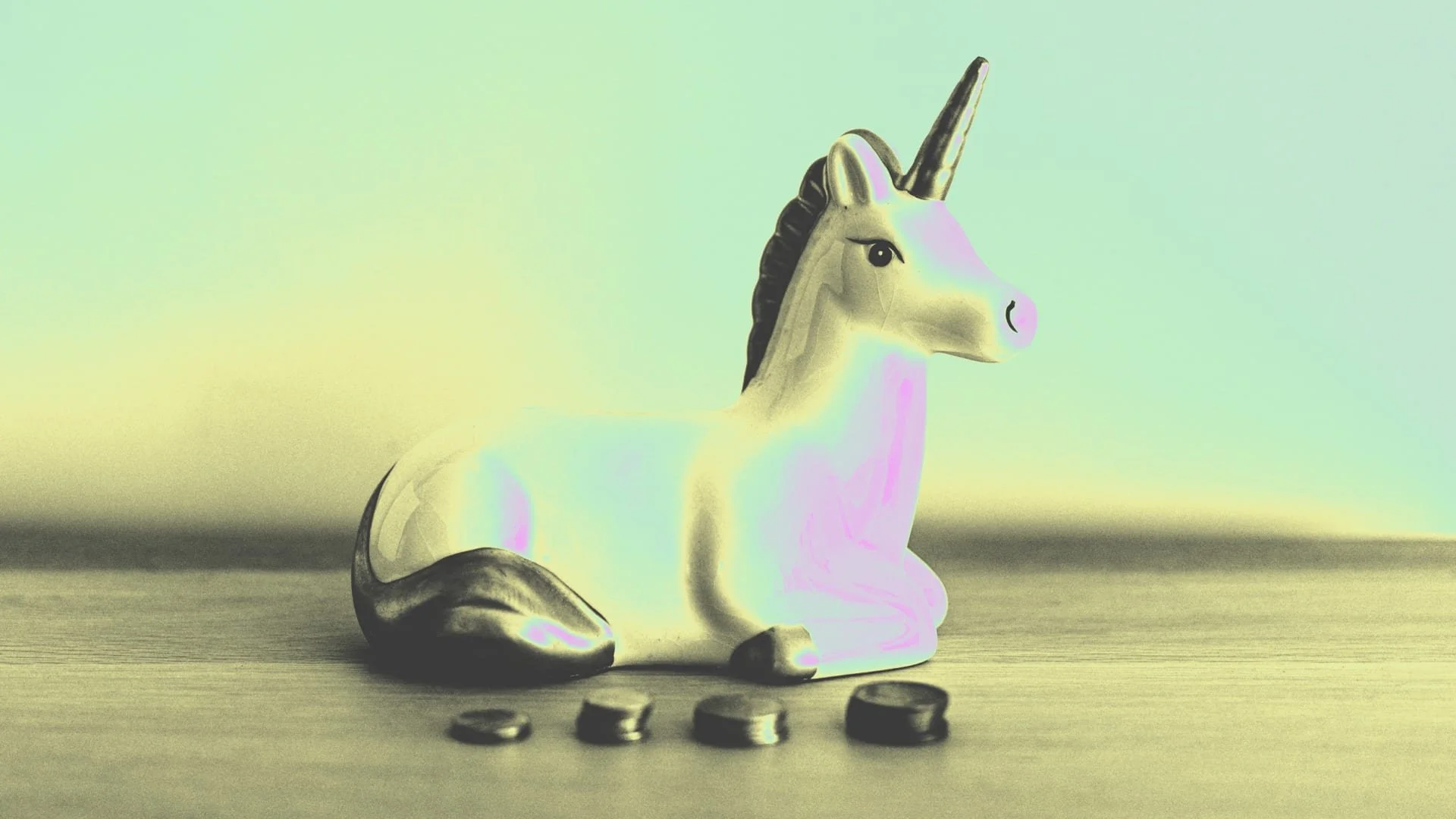 A ceramic unicorn figurine with a metallic horn, black mane, and tail, sitting on a wooden surface with four coins in front of it against a plain background.