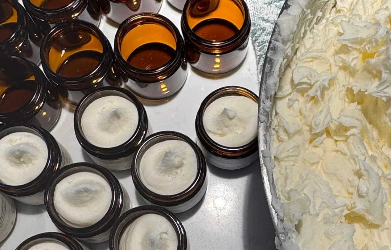 Several brown glass jars, some filled with a white tallow, on a countertop next to a large bowl of tallow.