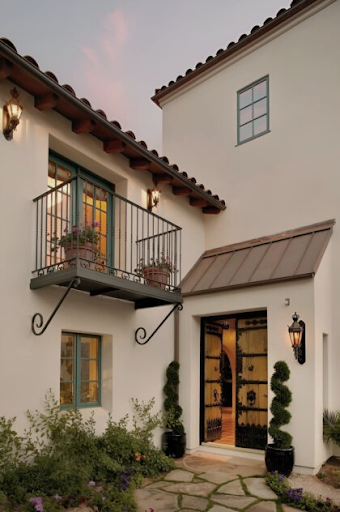 ront elevation of a white stucco home featuring a covered entry, metal balcony, and stone path.