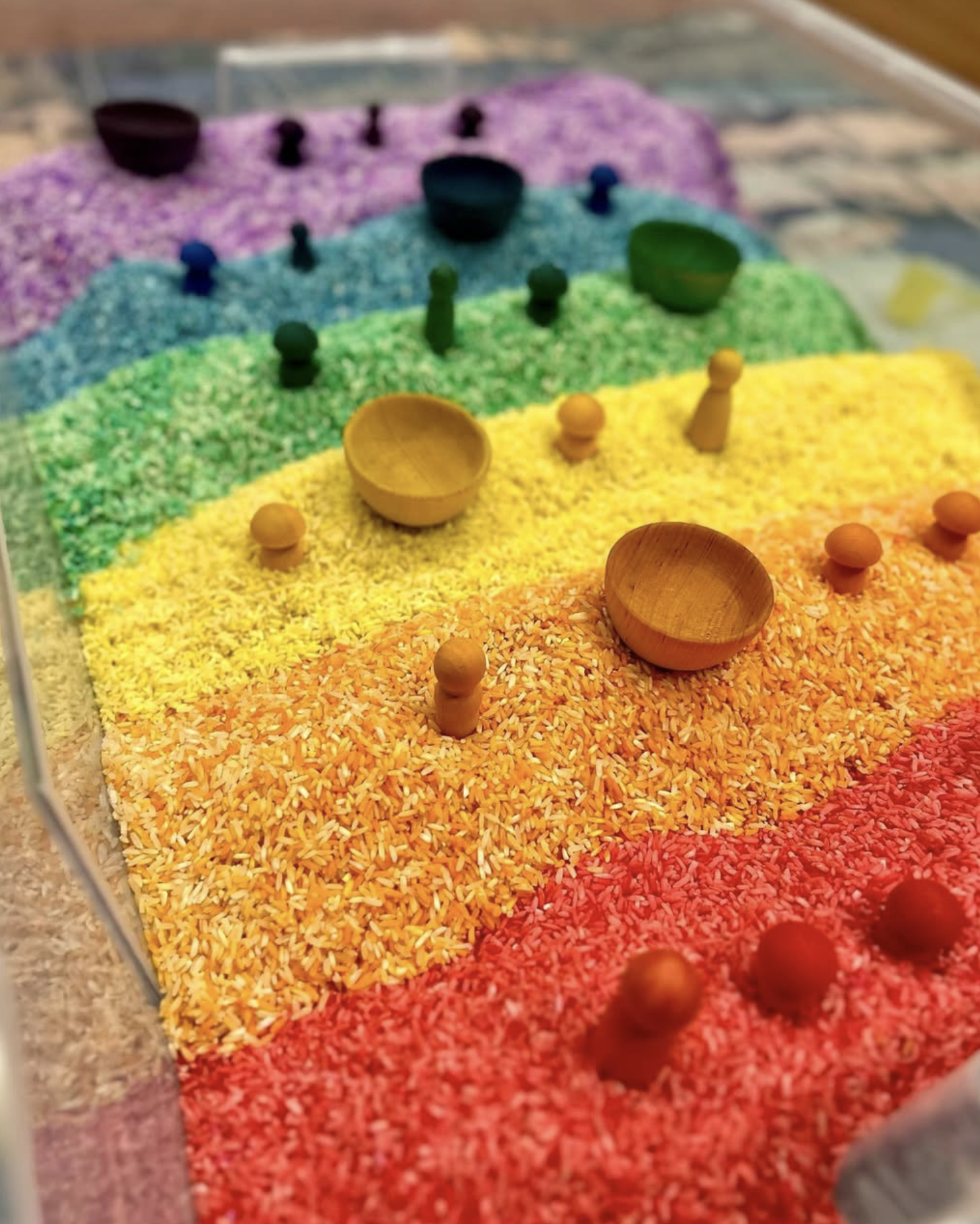 Colorful display of rainbow rice with small wooden bowls and pegs.