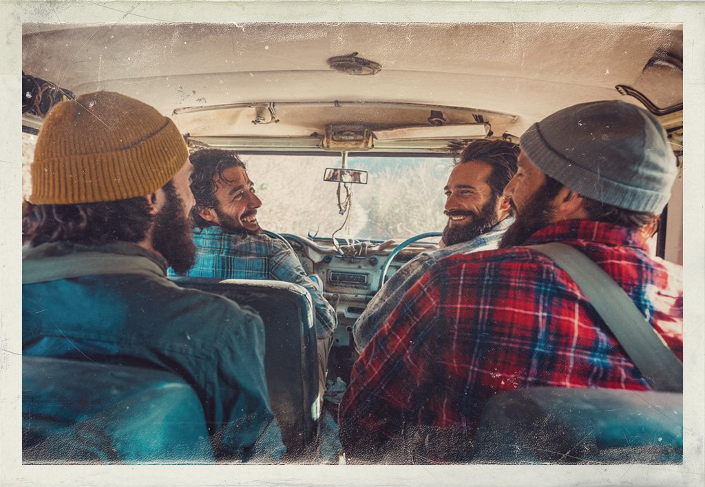 Four friends in winter hats and plaid jackets smile inside a van, viewed from the back seat