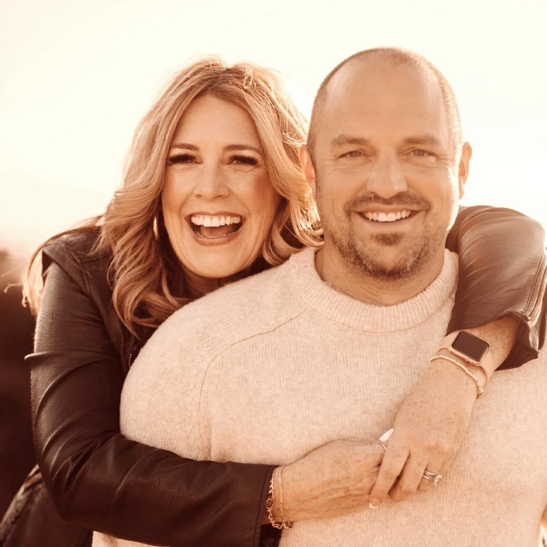 Two smiling people embracing, warmly lit against a bright background