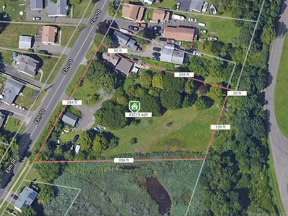 Aerial view of a residential property outlined in red with measurements, including surrounding houses, driveways, roads, and trees, showing a large lot with a house and a grassy area.