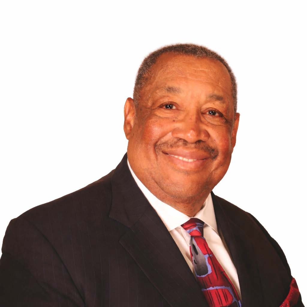 A middle-aged African American man smiling, wearing a black suit, white shirt, and colorful tie, against a plain white background.