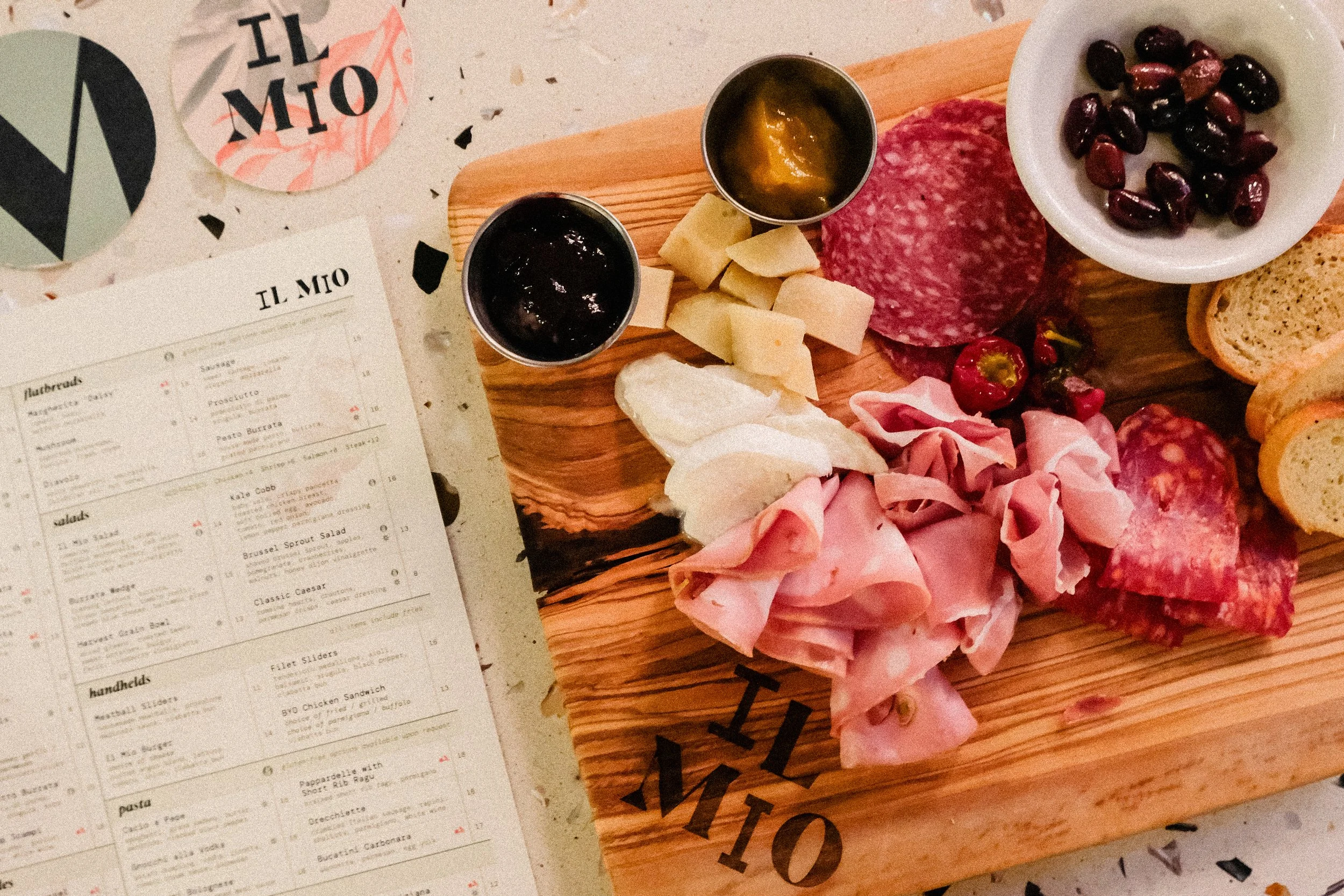 Menu and coasters arranged next to a charcuterie board in Il Mio