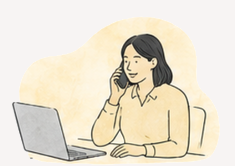 A woman sitting at a desk, talking on the phone, with a laptop in front of her.