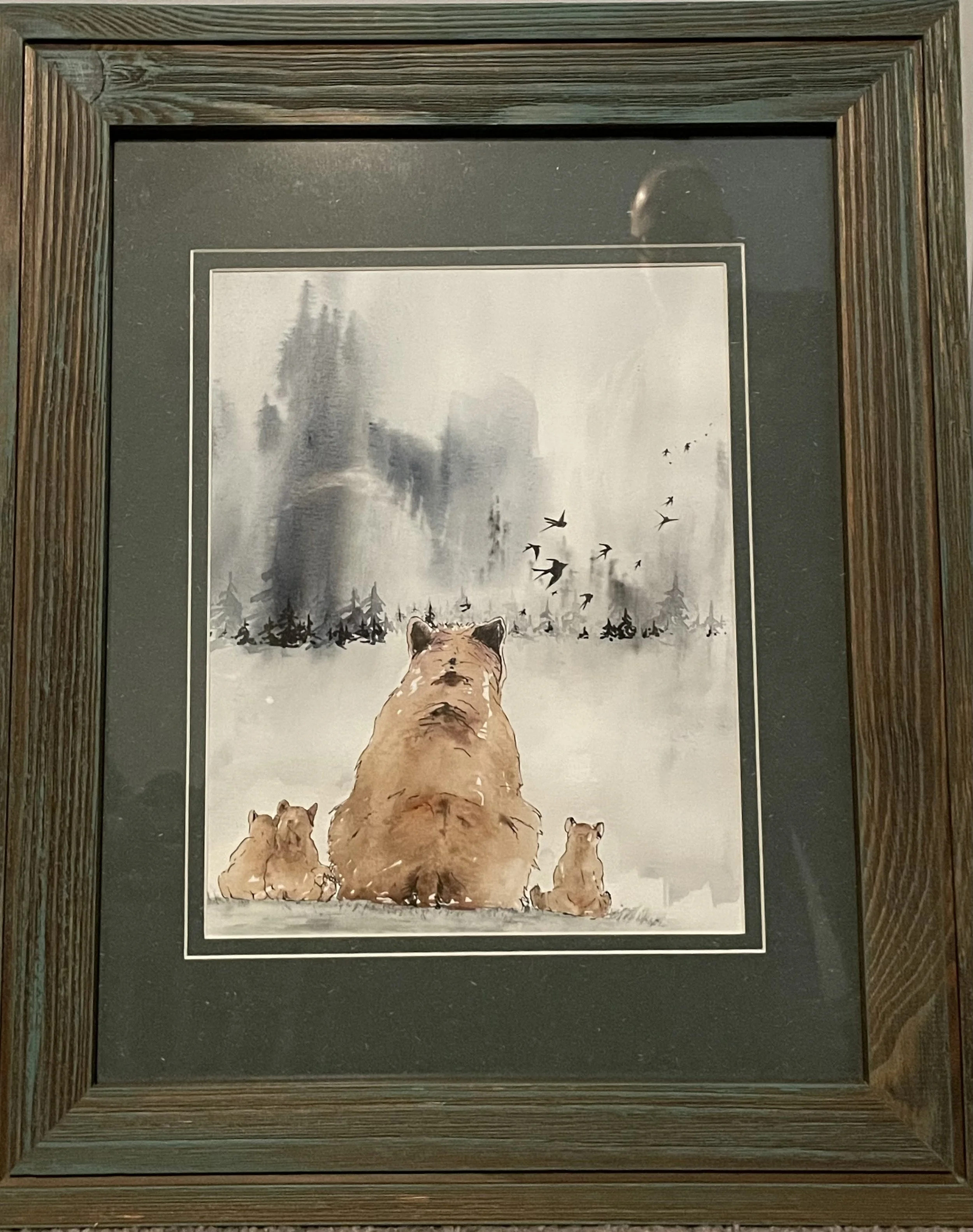 Watercolor painting of a family of bears, including two cubs and an adult, sitting on snow with a misty forest and flying birds in the background.