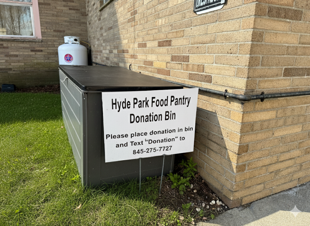 A sign attached to a black donation bin outside a brick building. The sign reads 'Hyde Park Food Pantry Donation Bin. Please place donation in bin and text "Donation" to 845-275-7727.'