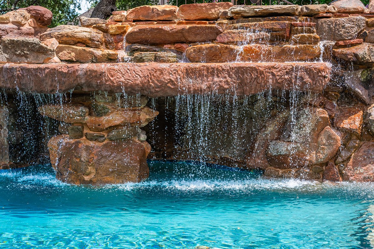 Waterfall flowing over rocks into a blue pool of water.