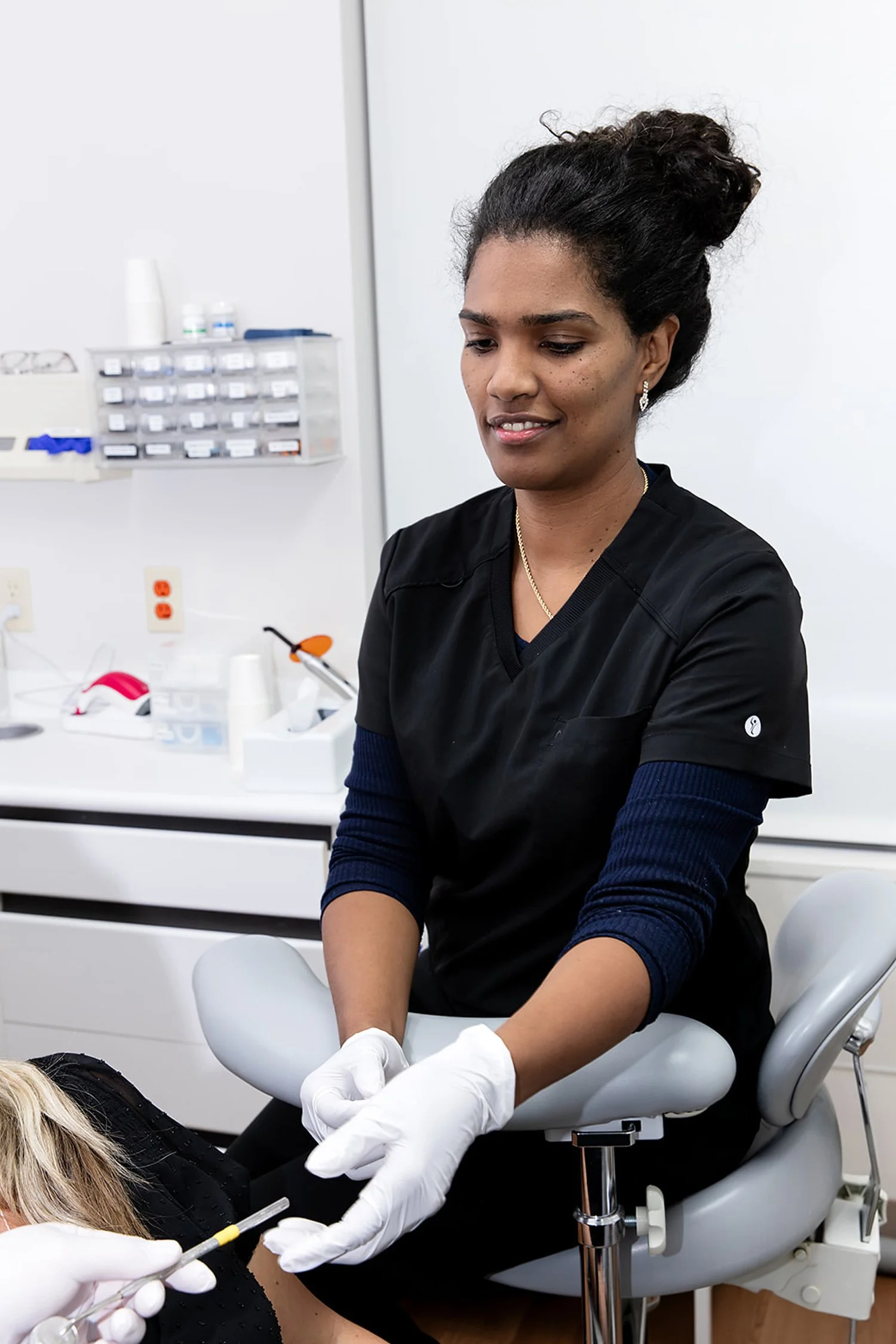 A medical professional, wearing black scrubs and gloves, is administering a vaccination to a patient in a clinical setting.