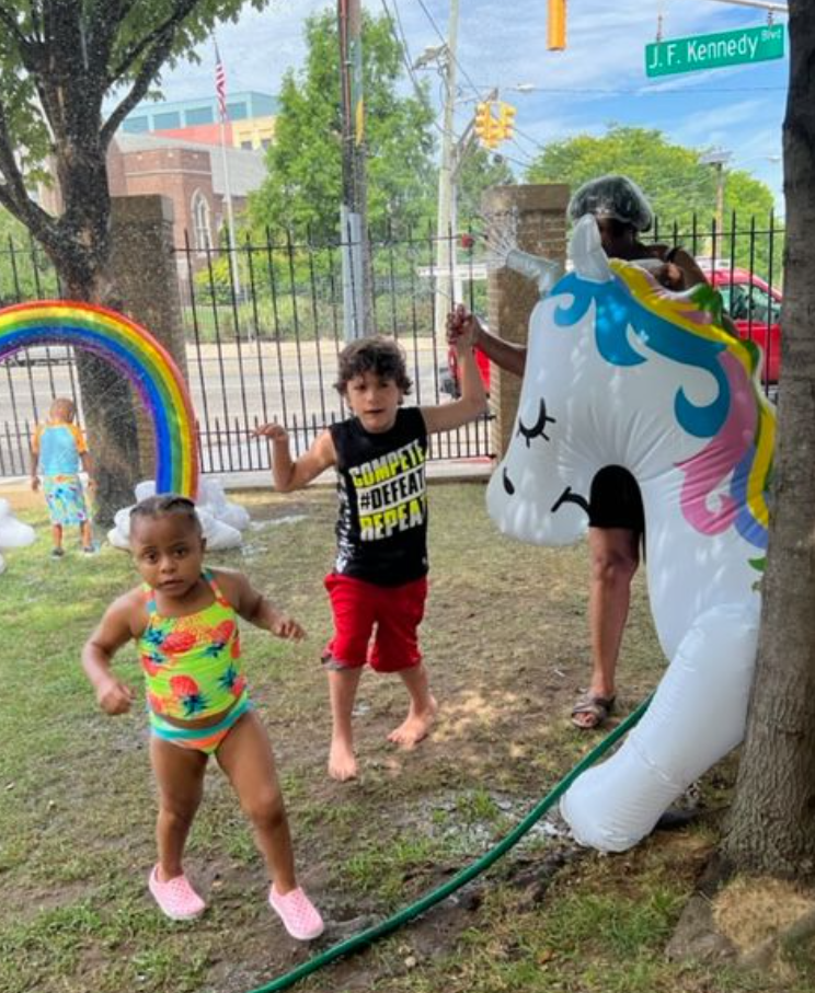 Students run through a rainbow sprinkler on a summer day