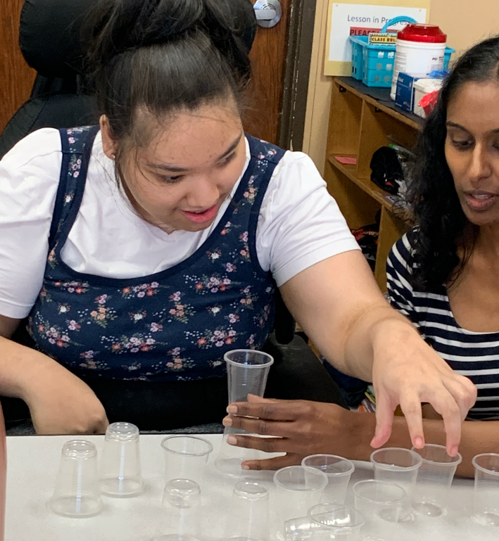 A student stacks cups with her occupational therapist