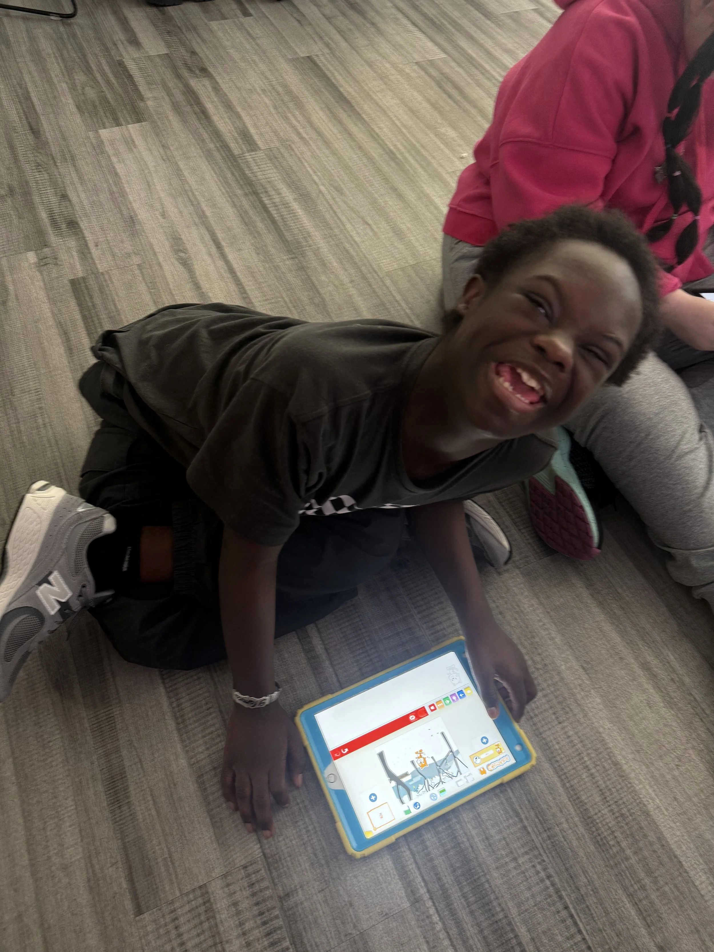 A student works on a tablet on the classroom floor